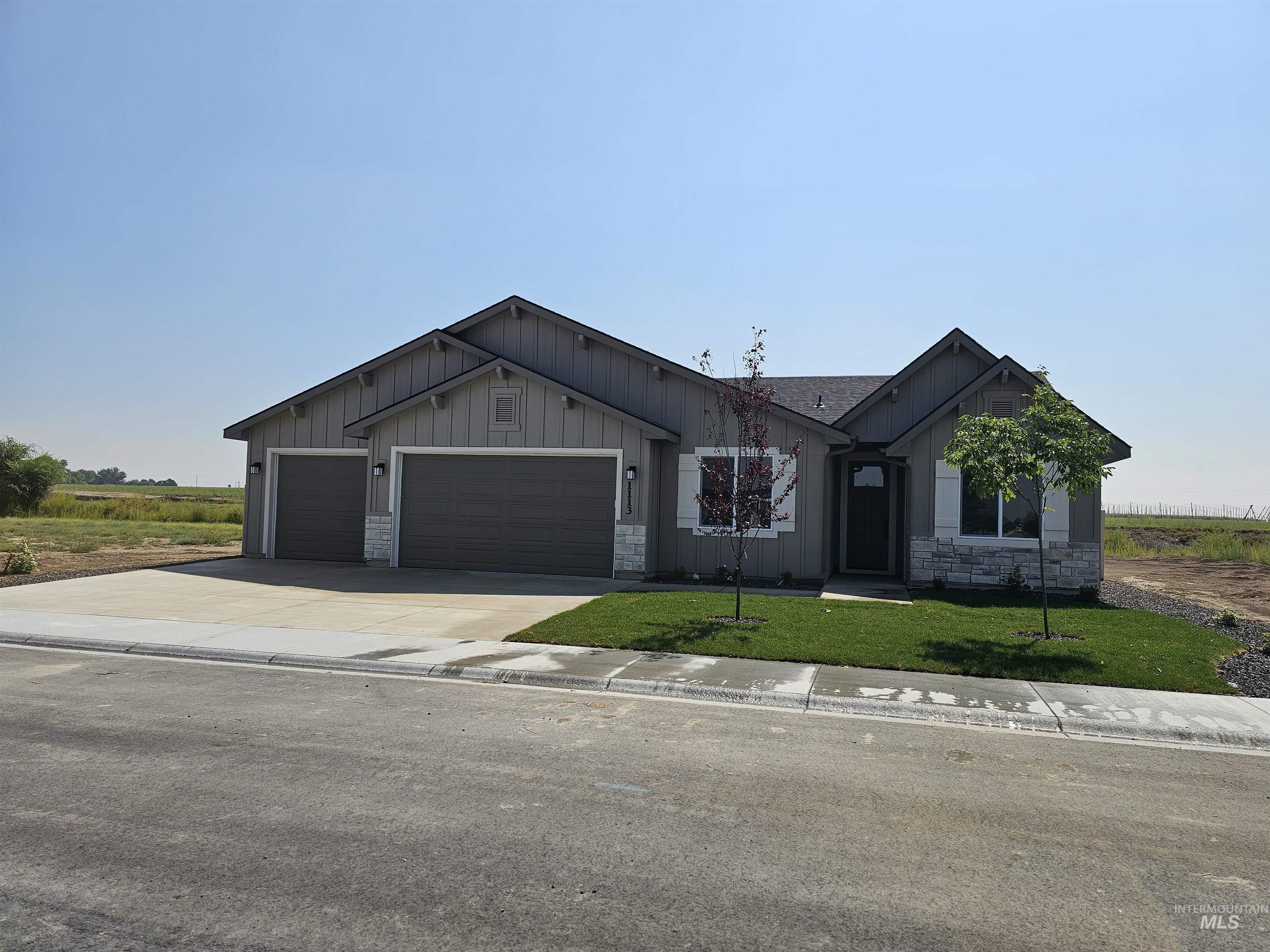 View of front of home featuring board and batten siding, driveway, stone siding, and a garage