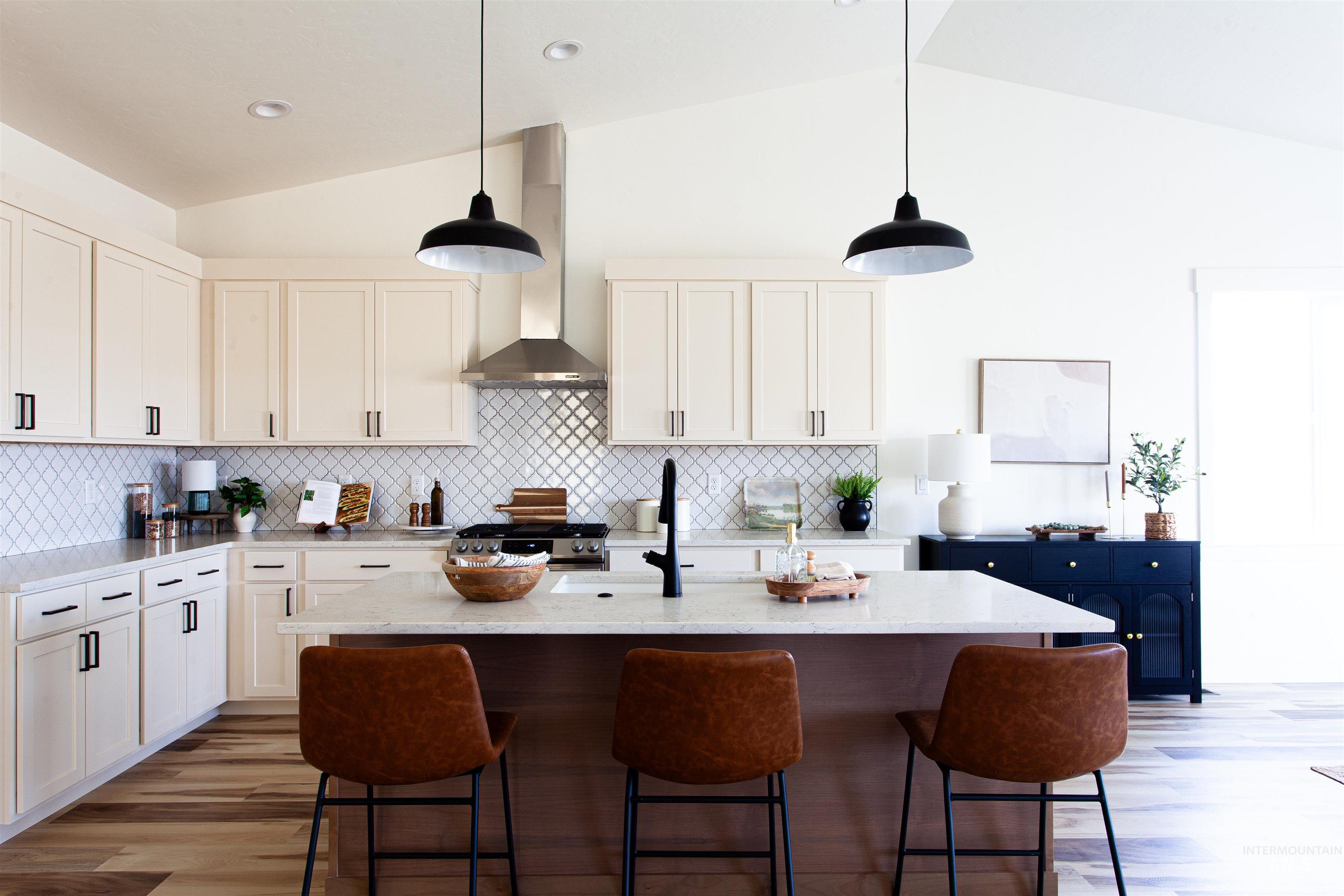 Kitchen featuring vaulted ceiling, wood finished floors, a kitchen island with sink, pendant lighting, and decorative backsplash