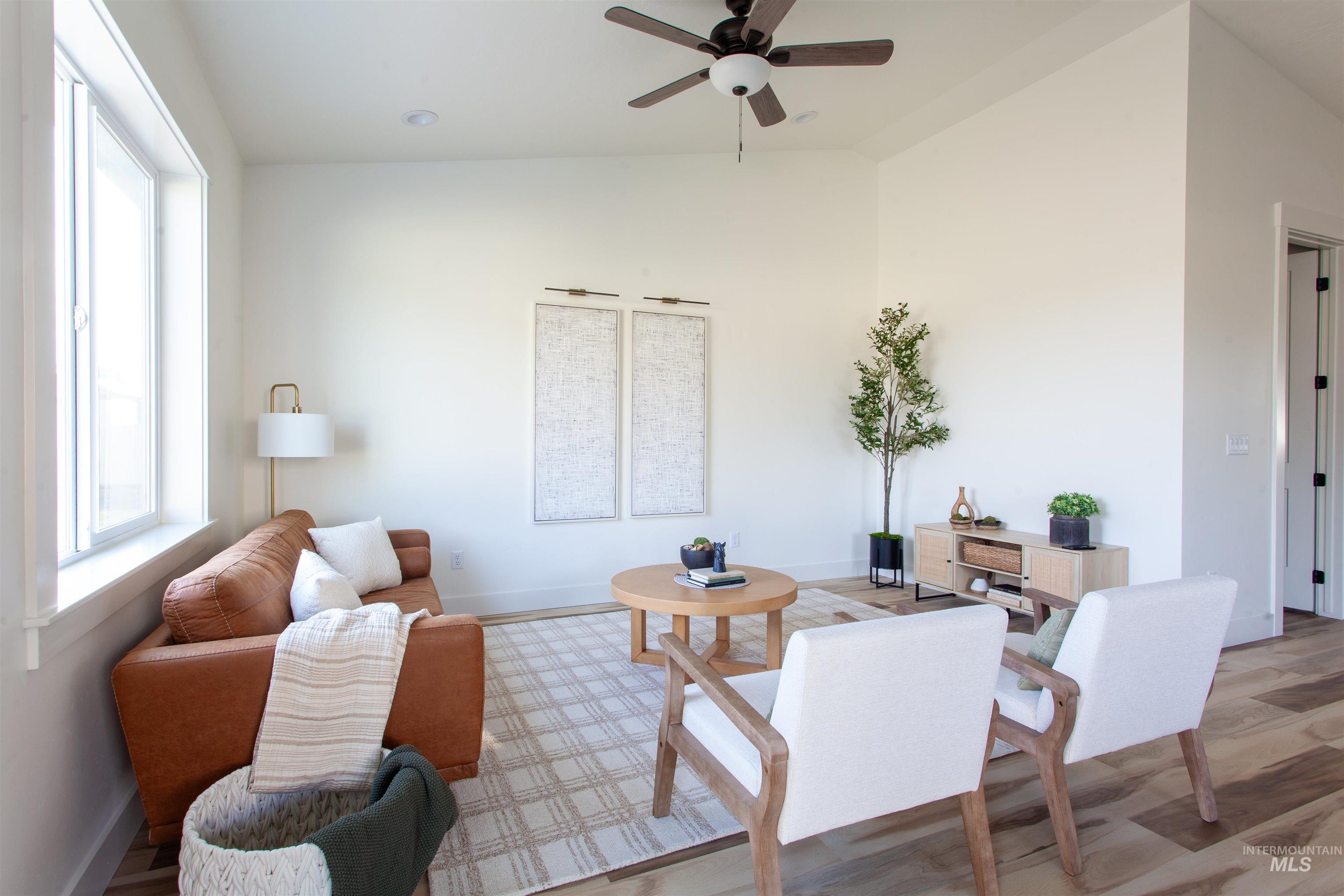 Living area featuring vaulted ceiling, wood finished floors, and ceiling fan