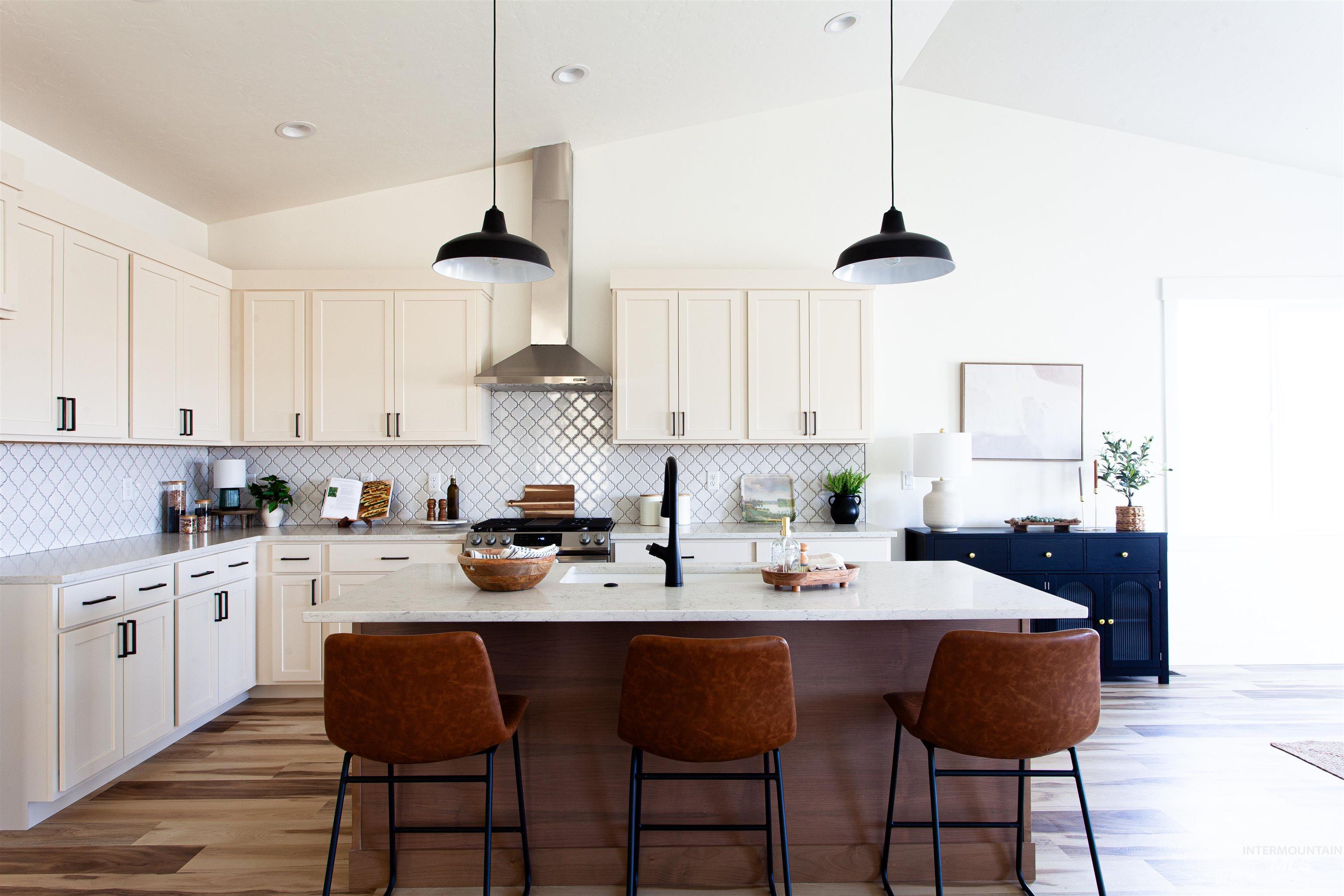 Kitchen featuring vaulted ceiling, pendant lighting, light wood-type flooring, an island with sink, and light stone countertops