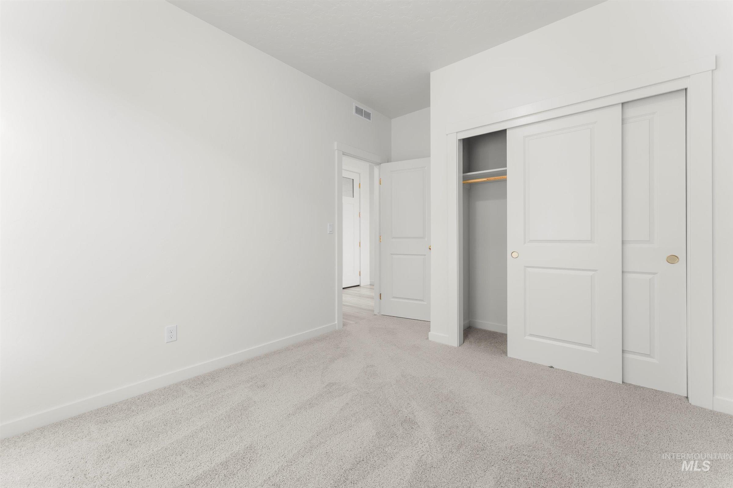 Unfurnished bedroom with light colored carpet and a closet