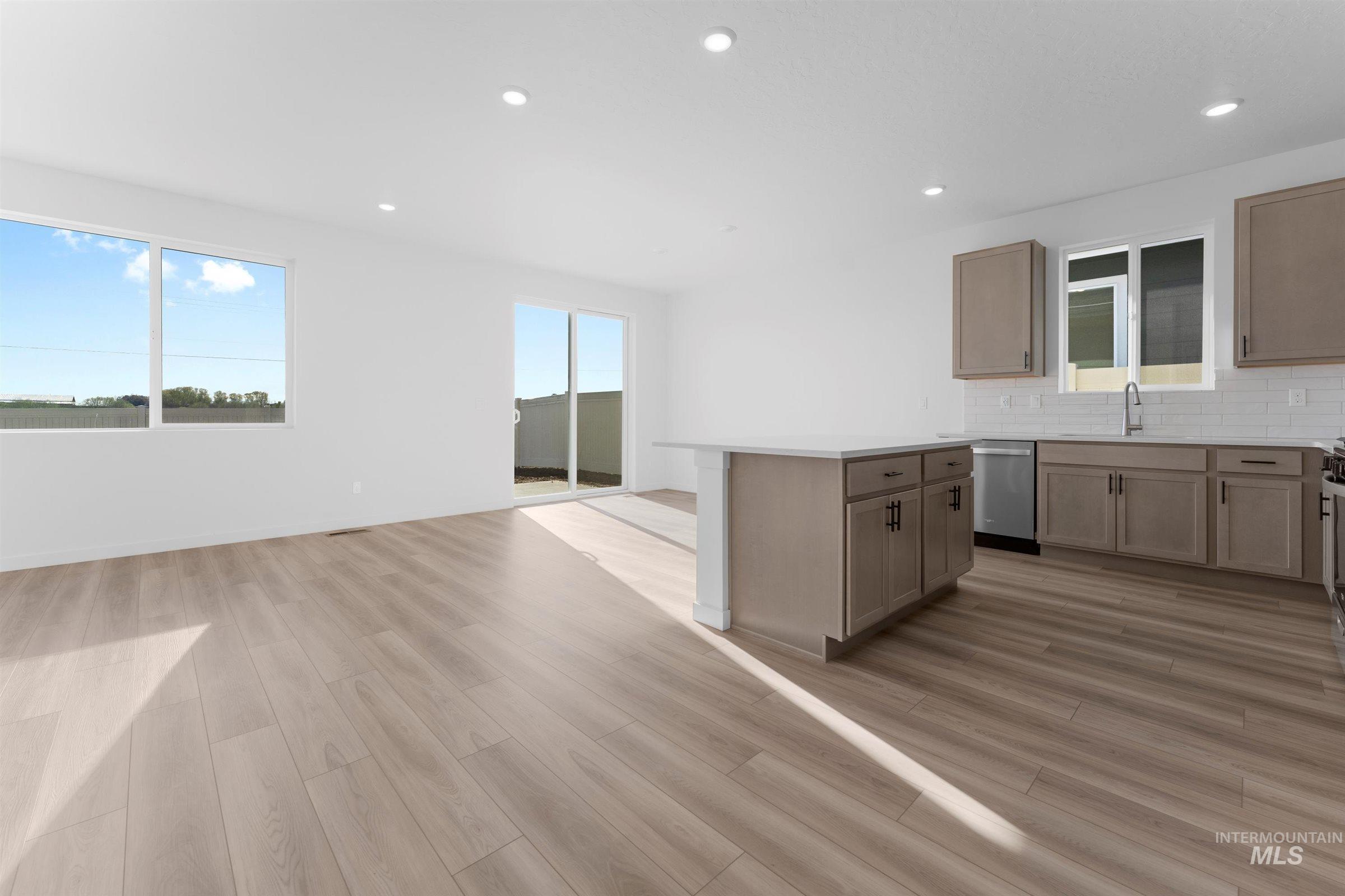 Kitchen featuring backsplash, recessed lighting, a center island, stainless steel dishwasher, and light wood-style flooring