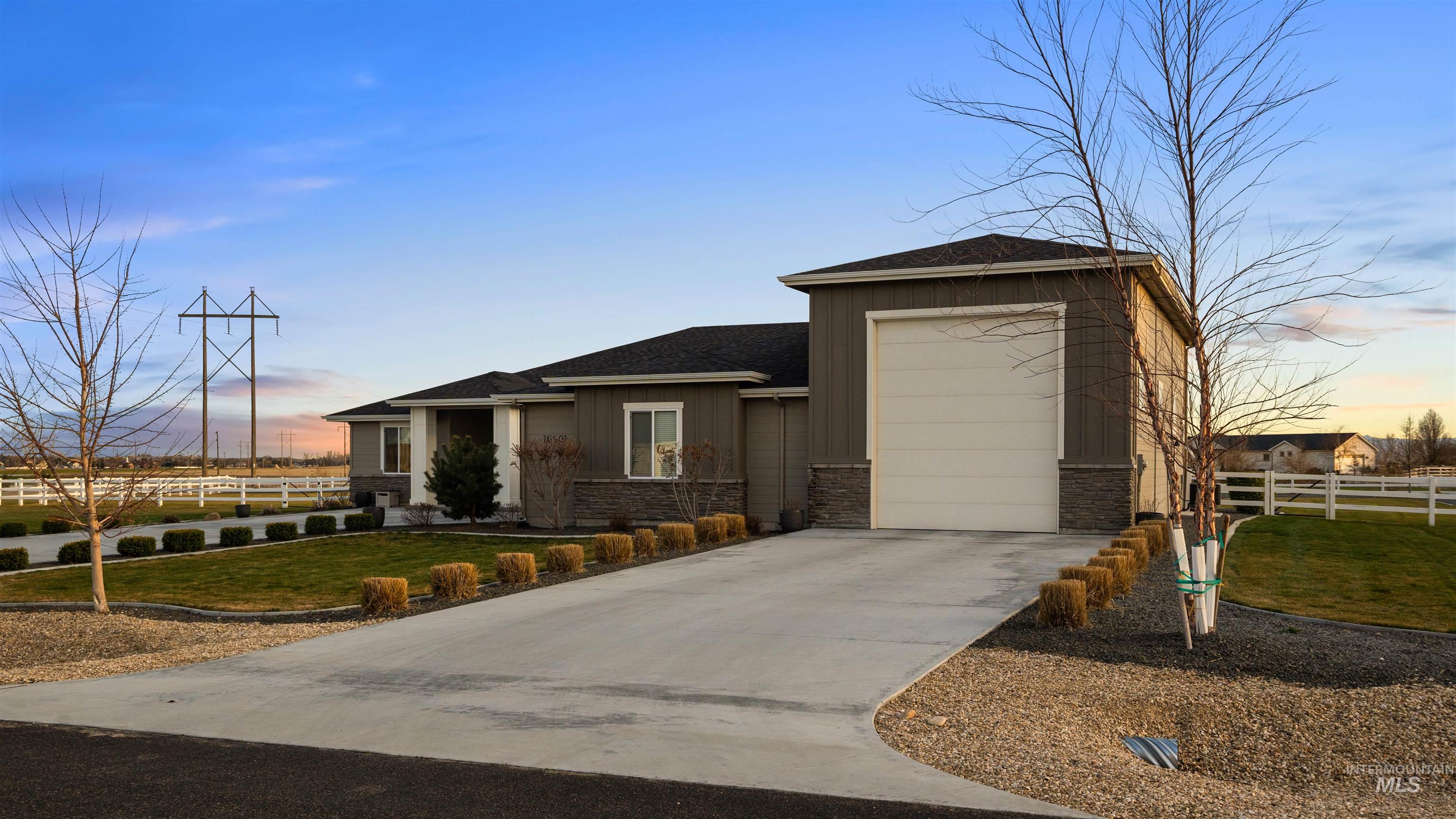 View of front of property featuring a shingled roof, stone siding, driveway, and board and batten siding