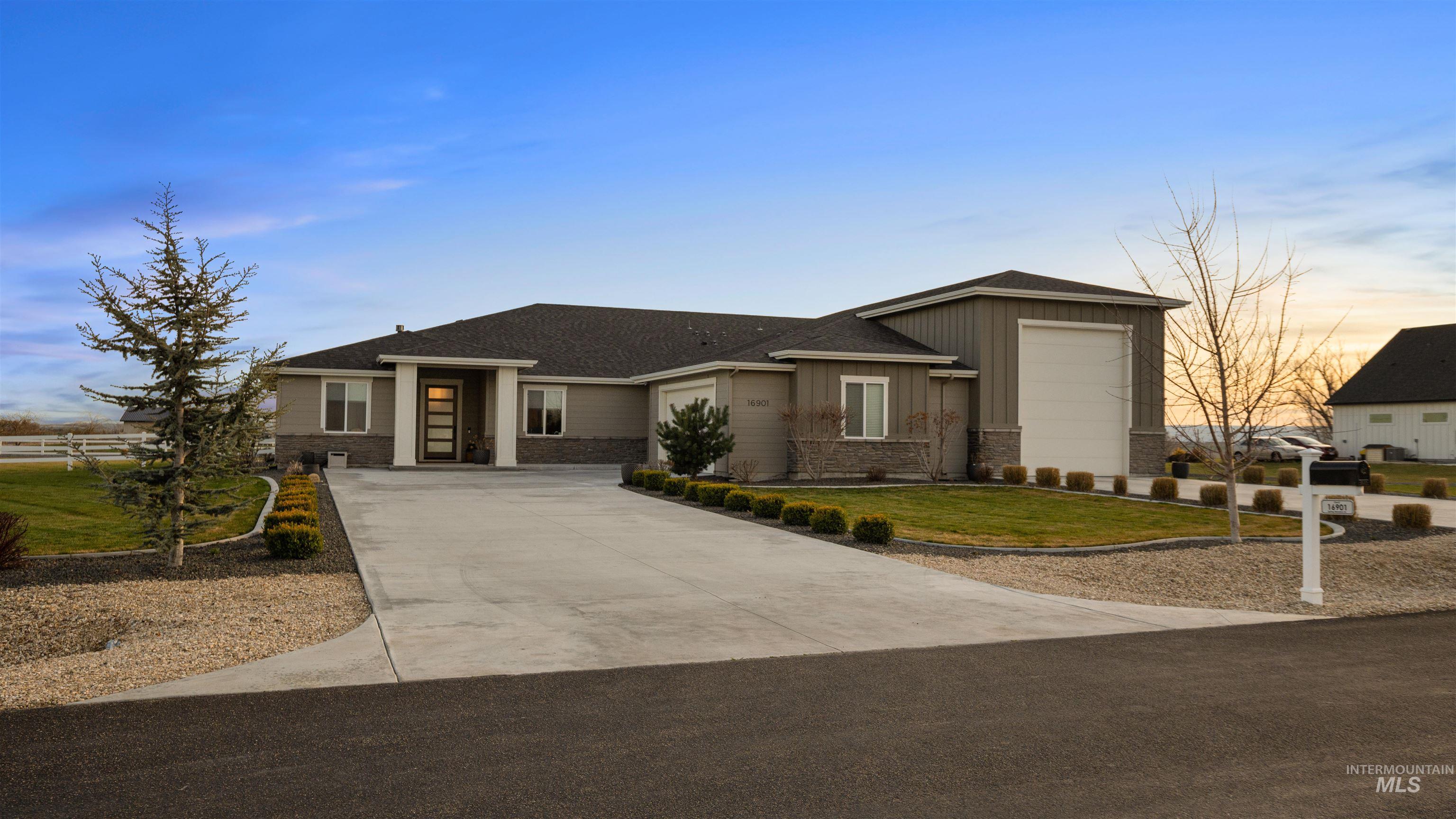 Prairie-style house featuring board and batten siding, a front yard, concrete driveway, roof with shingles, and a garage