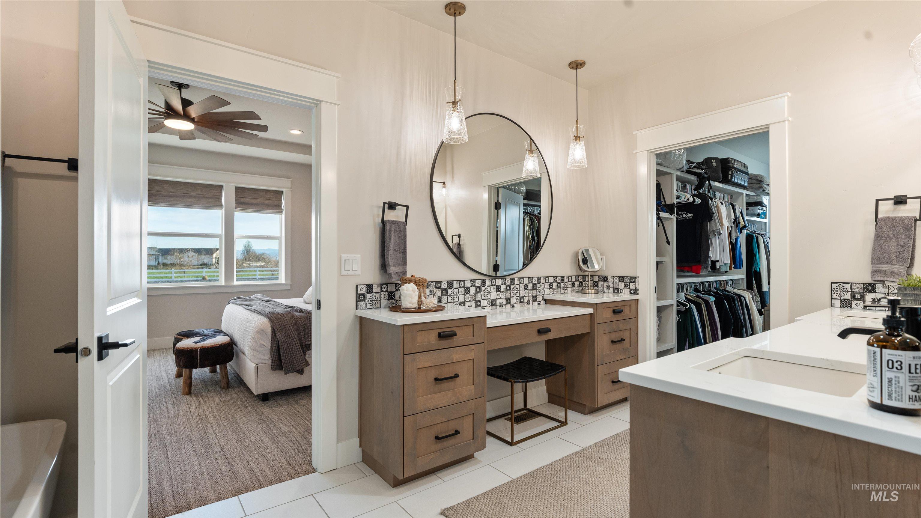 Ensuite bathroom featuring vanity, decorative backsplash, and light tile patterned floors