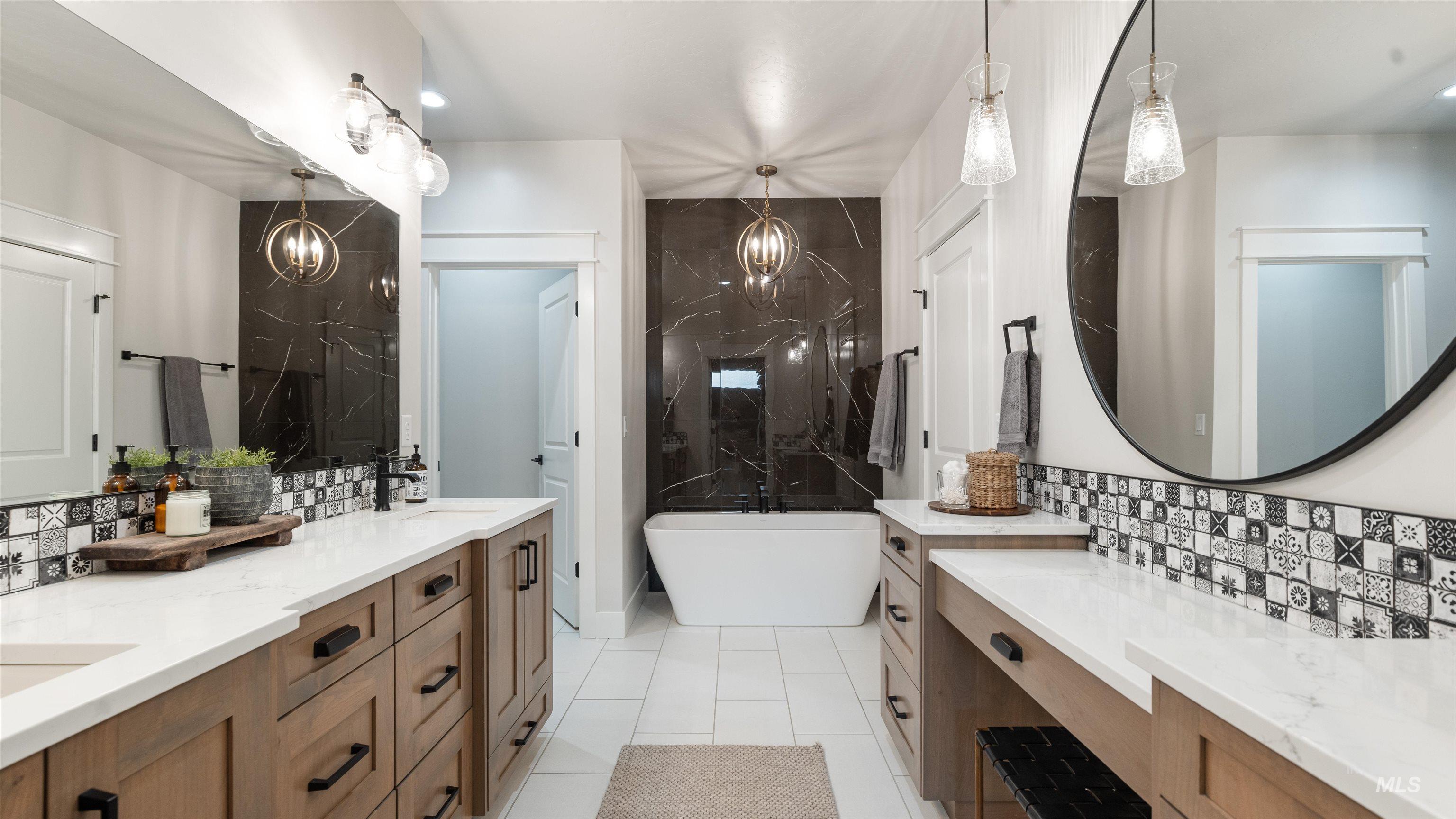 Full bath featuring double vanity, tasteful backsplash, a soaking tub, and light tile patterned floors