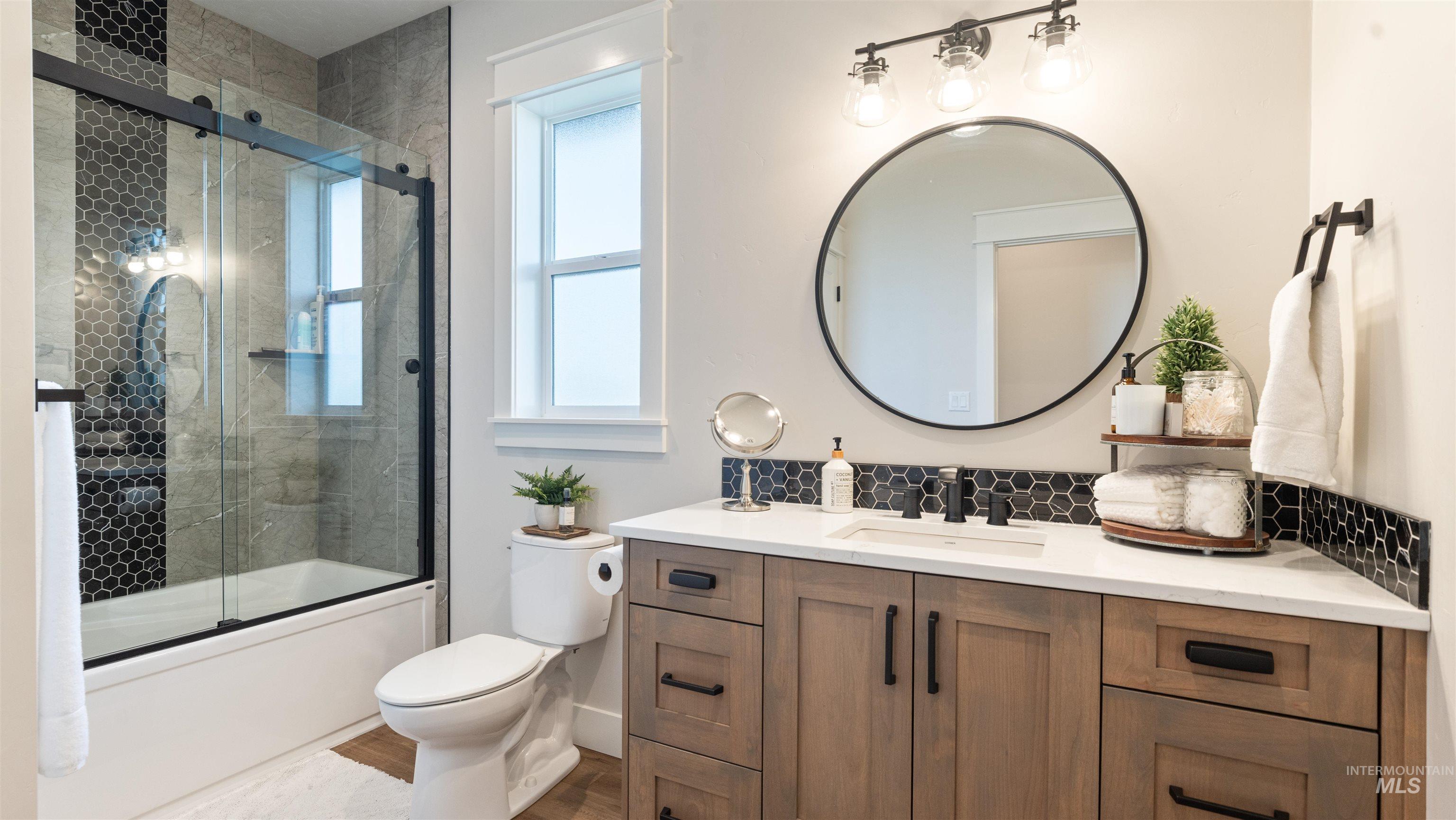 Full bath featuring vanity, shower / bath combination with glass door, and wood finished floors