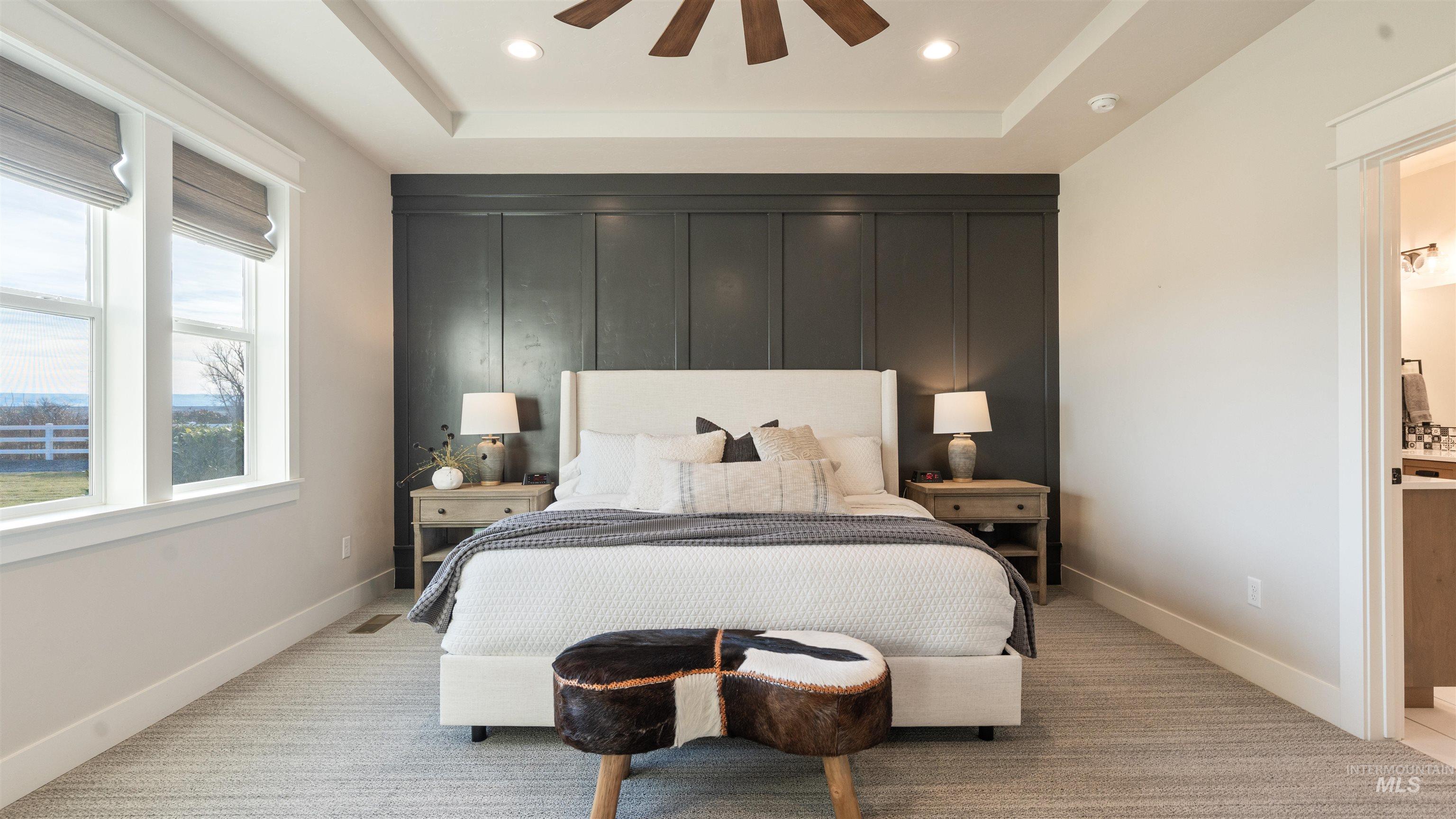 Bedroom featuring a raised ceiling, light carpet, recessed lighting, connected bathroom, and a ceiling fan