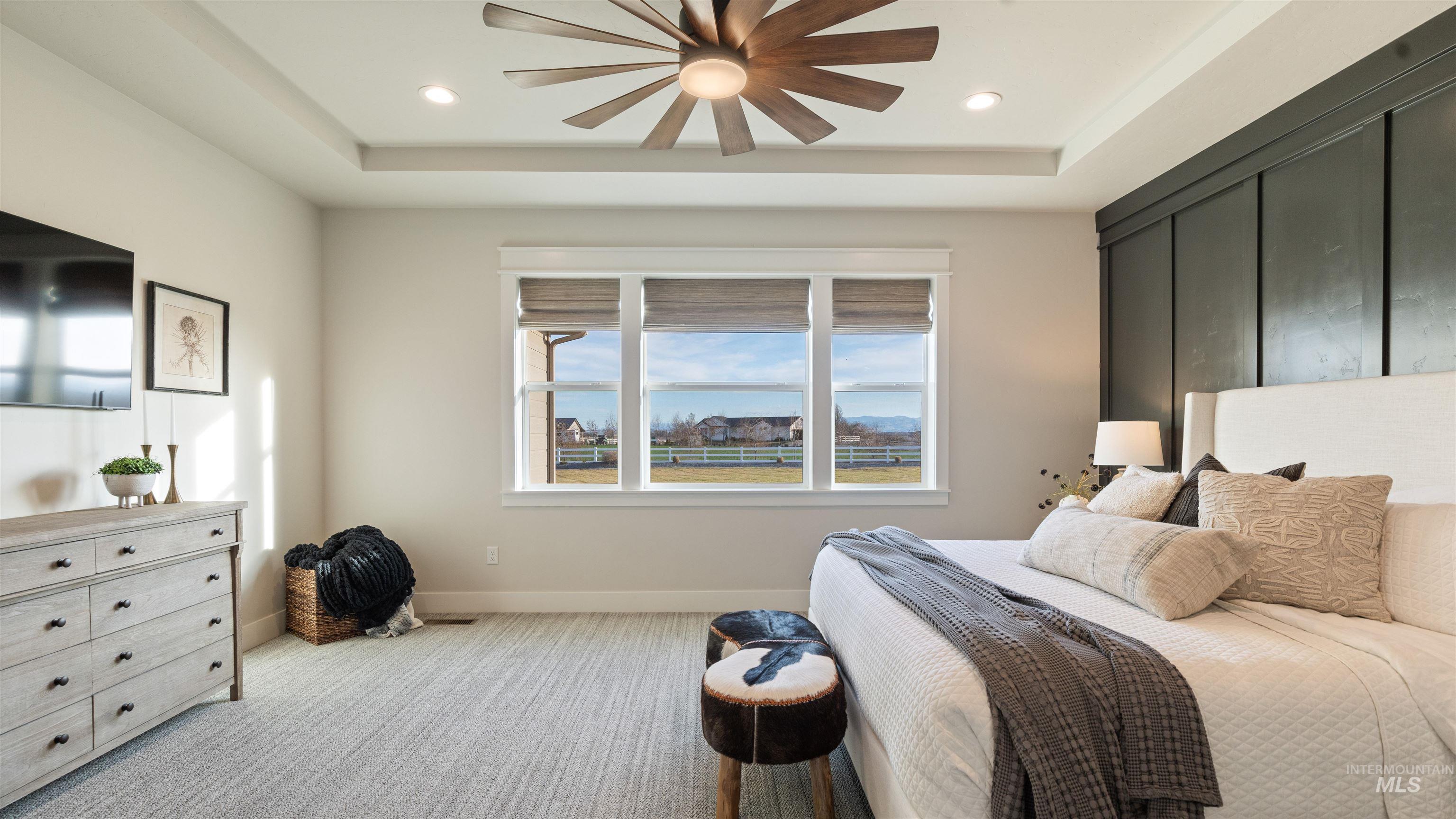 Bedroom with a tray ceiling, light colored carpet, a ceiling fan, and recessed lighting