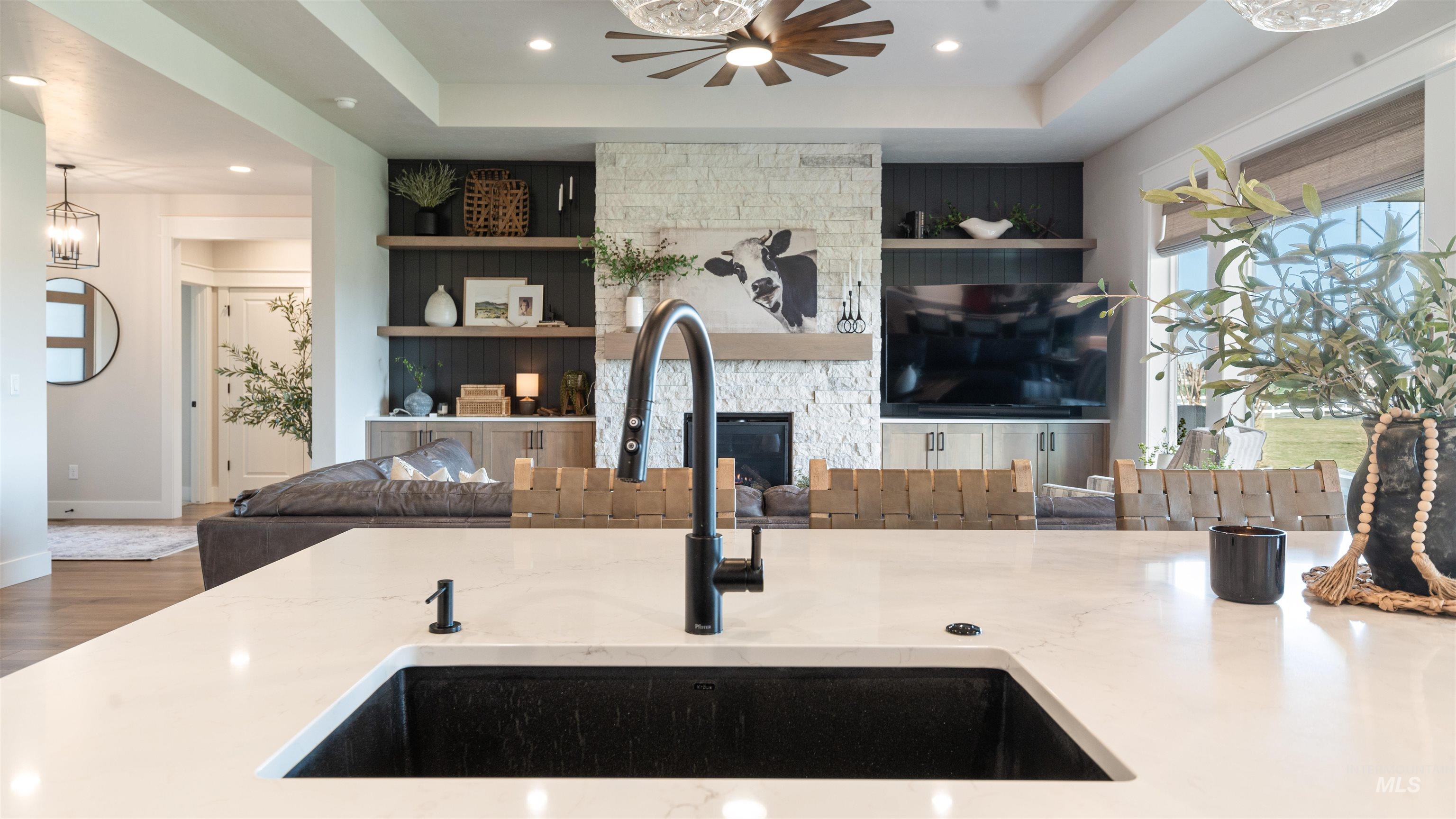 Living room with a raised ceiling, wood finished floors, a fireplace, recessed lighting, and built in features
