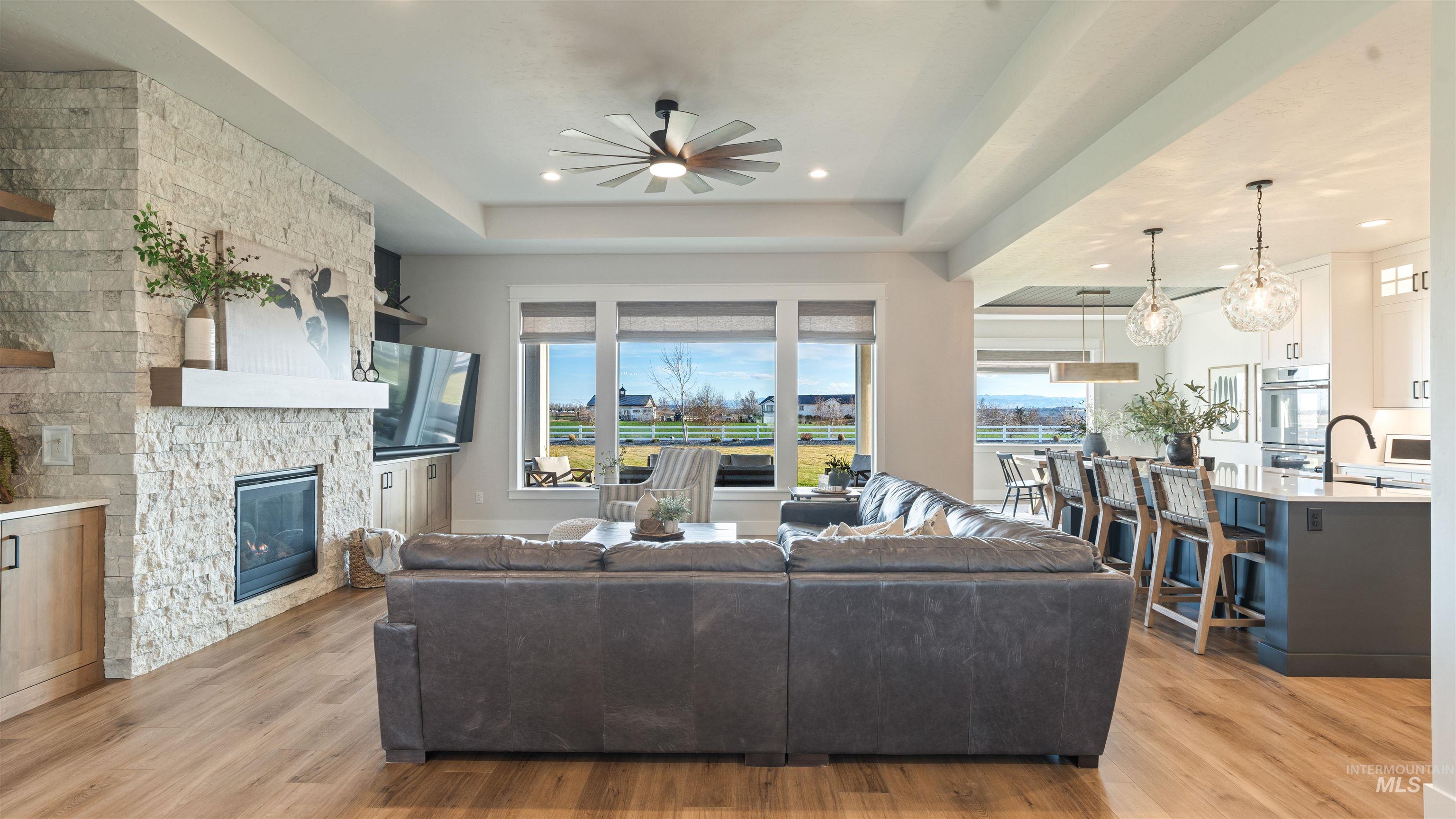 Living room with healthy amount of natural light, a ceiling fan, light wood-style floors, a fireplace, and recessed lighting