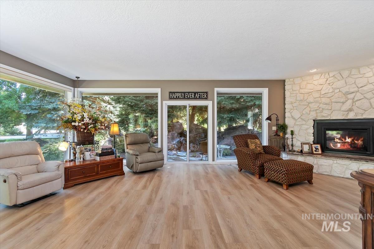 Living room with light wood finished floors, a fireplace, and a textured ceiling