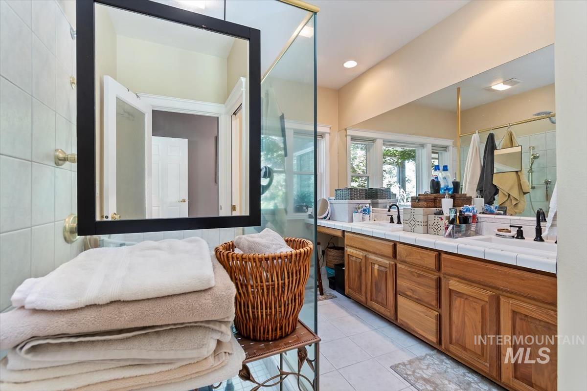 Bathroom featuring a shower stall, double vanity, and light tile patterned floors