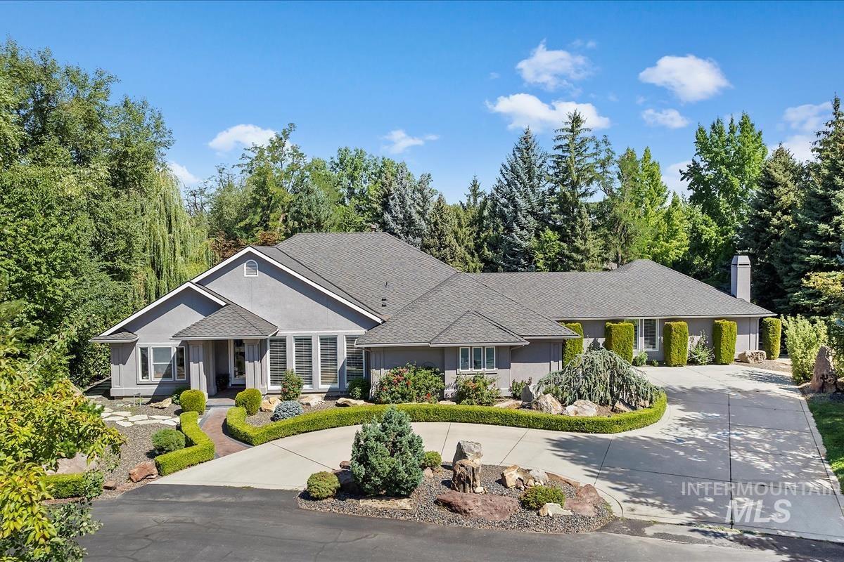 Ranch-style house with curved driveway, a chimney, and roof with shingles