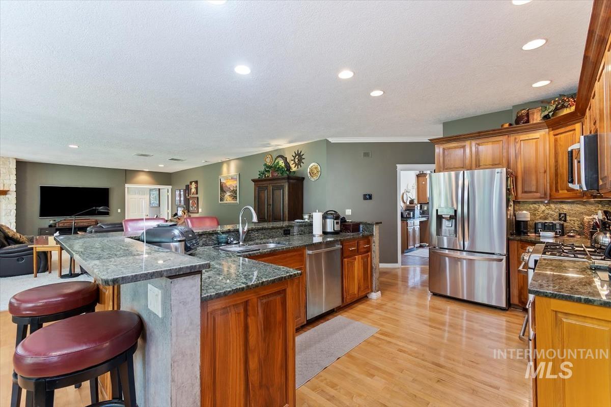 Kitchen featuring brown cabinets, stainless steel appliances, open floor plan, a kitchen breakfast bar, and recessed lighting