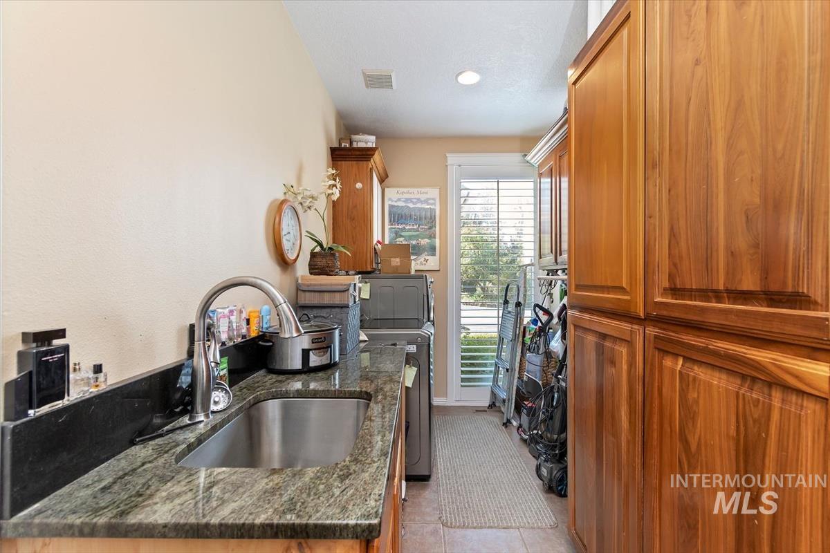 Kitchen with brown cabinets, dark stone countertops, and light tile patterned floors