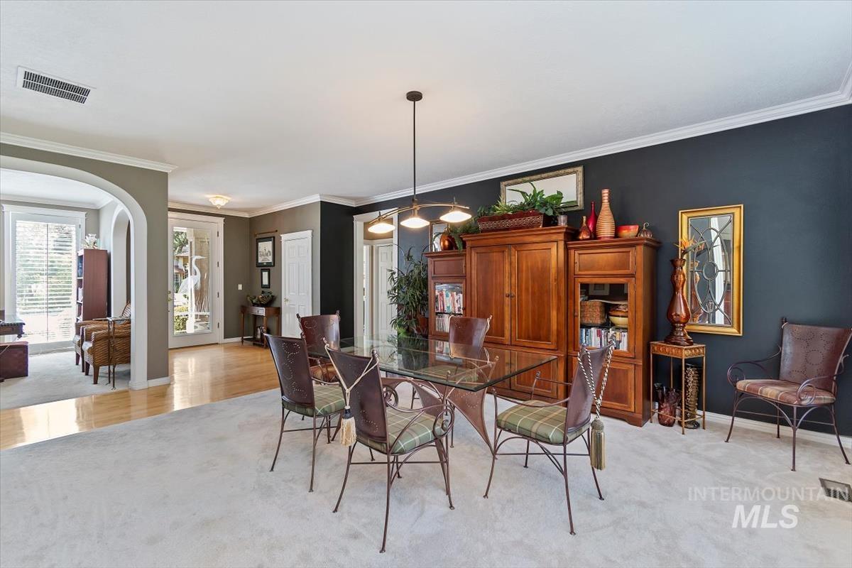 Dining room featuring crown molding, light colored carpet, and arched walkways