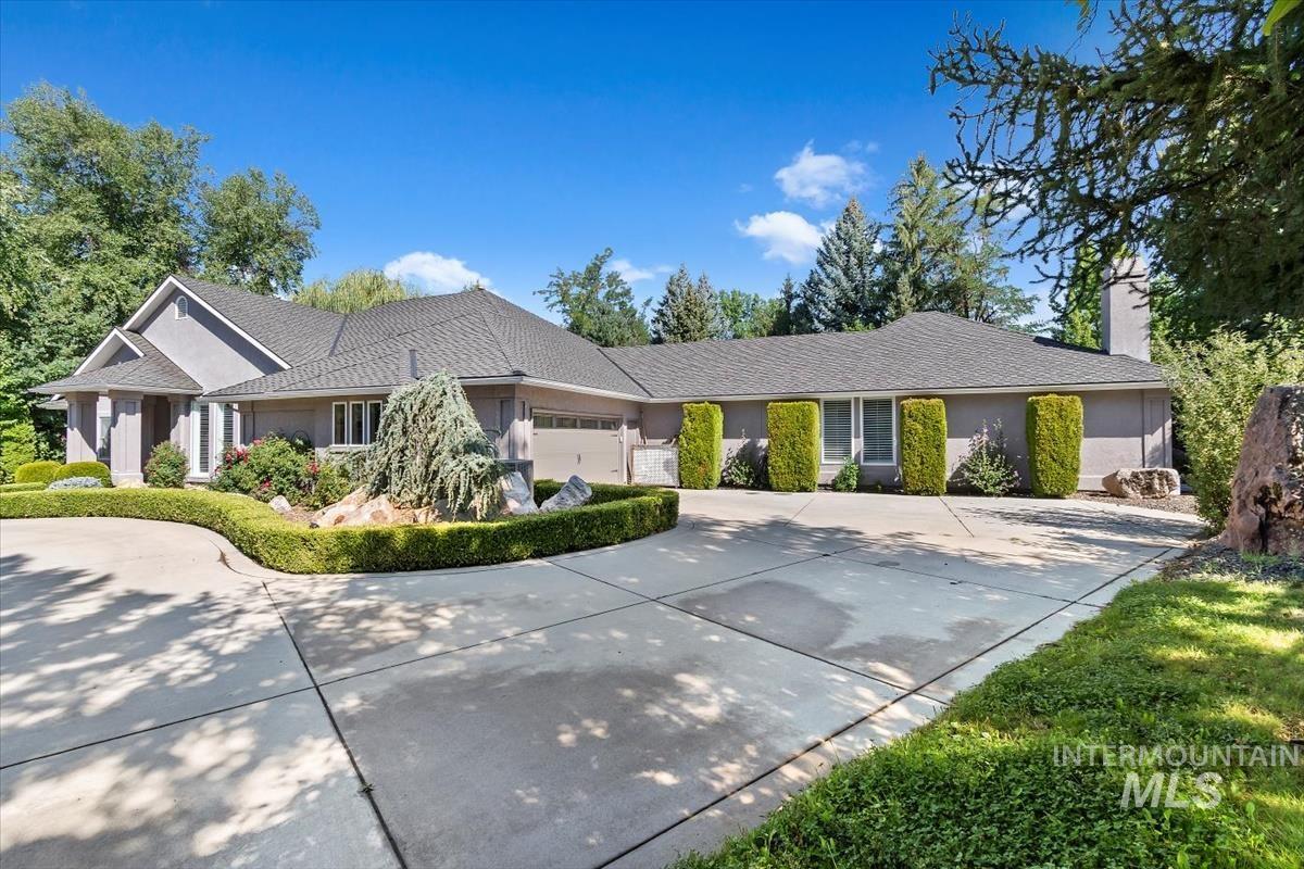 Single story home featuring an attached garage, concrete driveway, a chimney, and stucco siding
