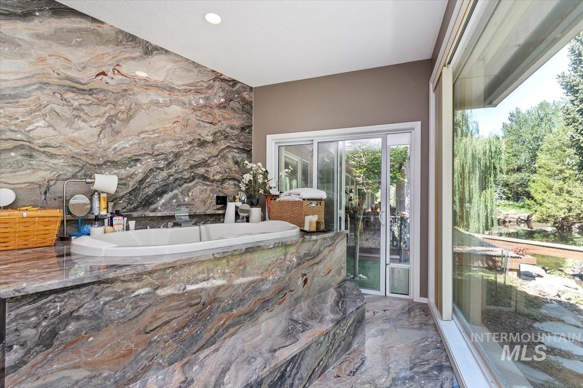Bathroom with a garden tub and marble tiled flooring