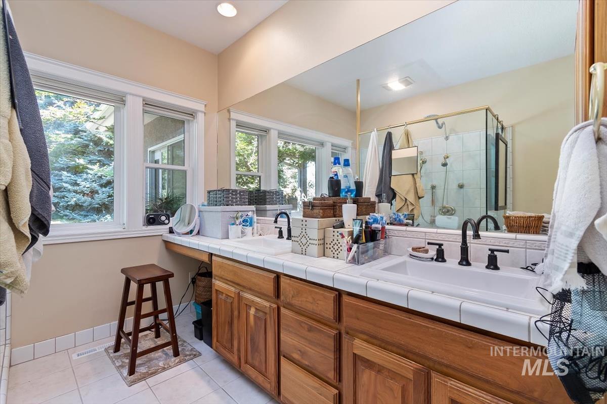 Full bathroom with a shower stall, double vanity, light tile patterned flooring, and recessed lighting