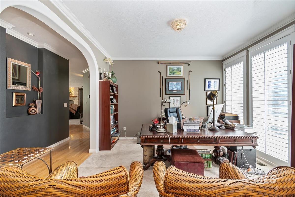 Office with arched walkways, crown molding, and wood finished floors