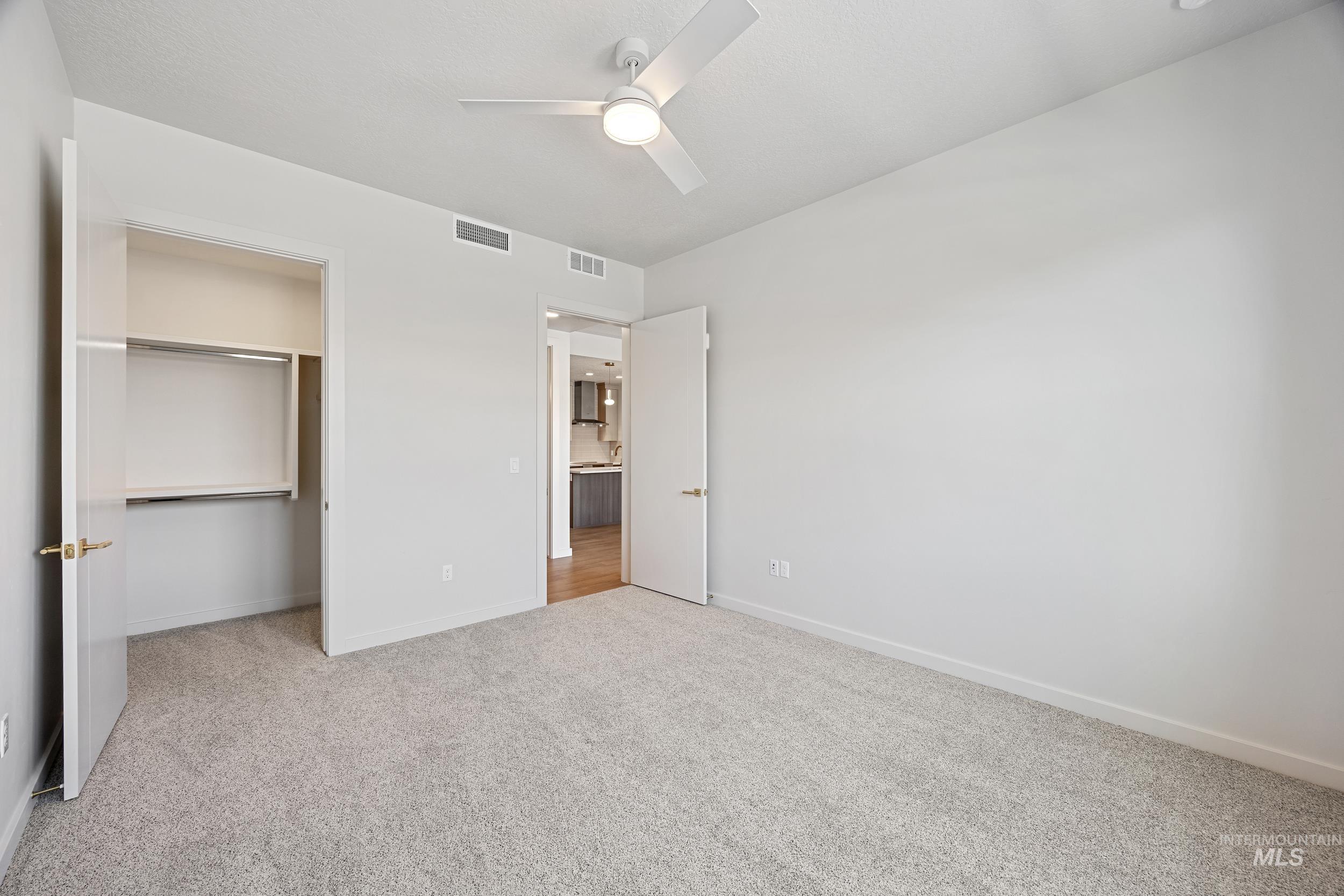 Unfurnished bedroom with light colored carpet, a ceiling fan, and a closet