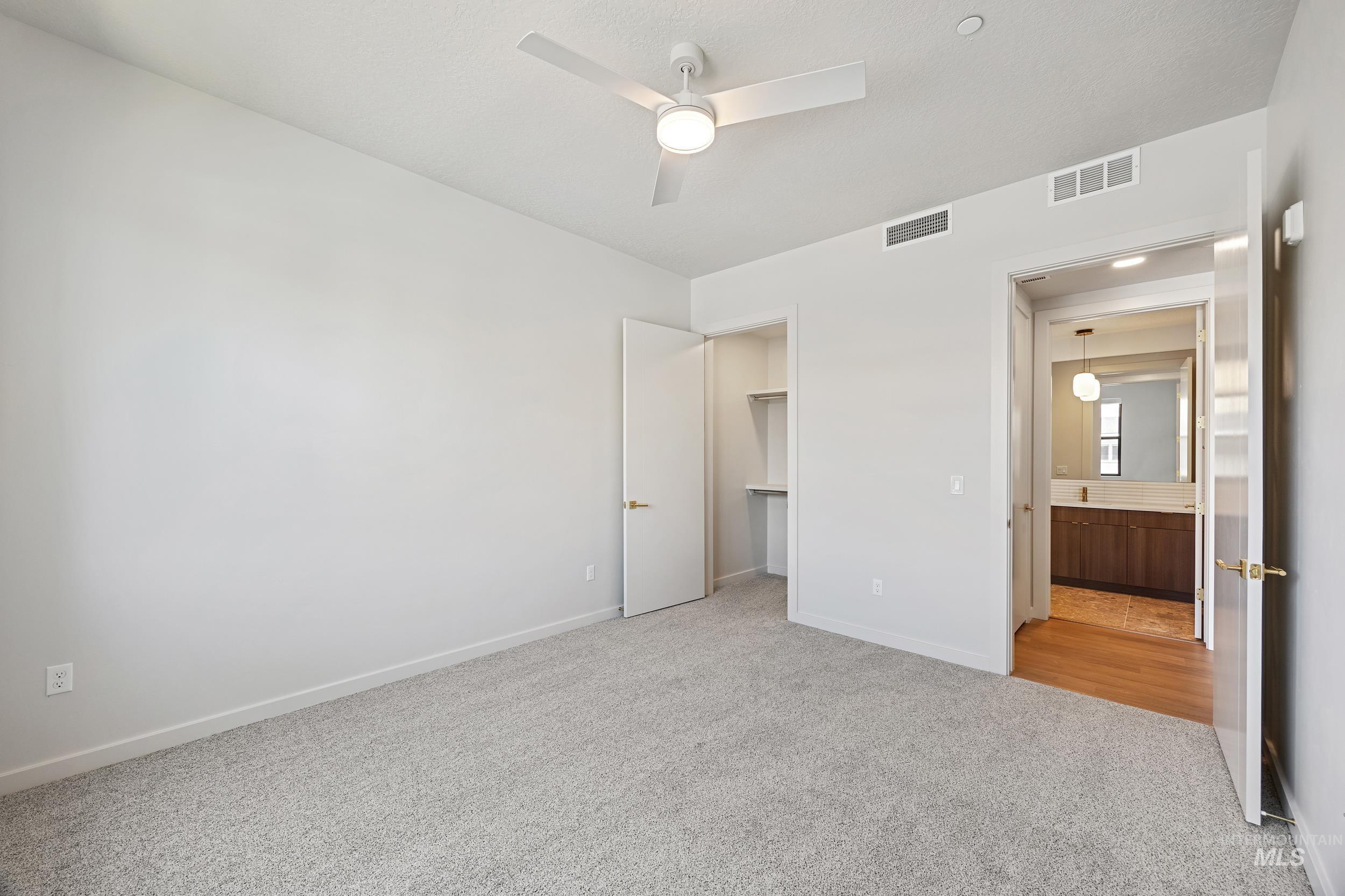 Unfurnished bedroom featuring light carpet, a spacious closet, and ceiling fan