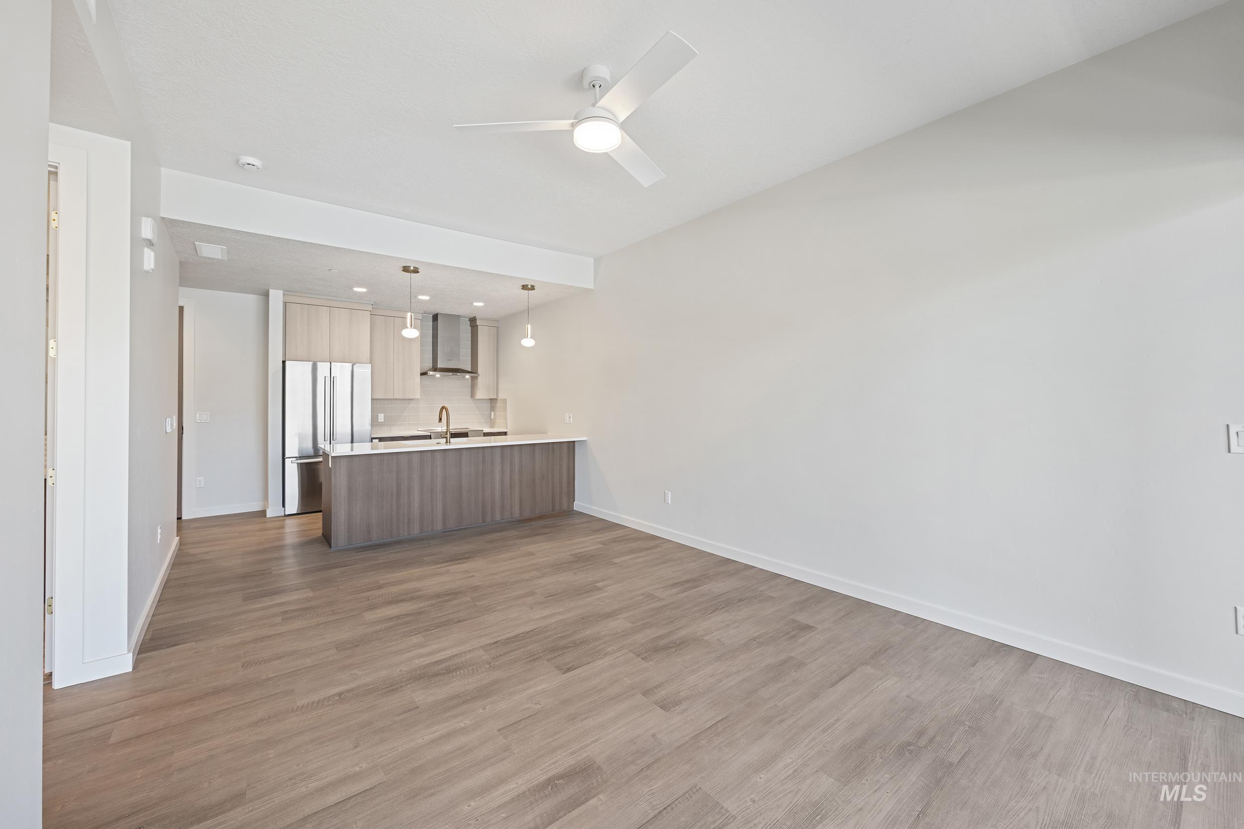 Unfurnished living room featuring dark wood-style flooring, a ceiling fan, and recessed lighting