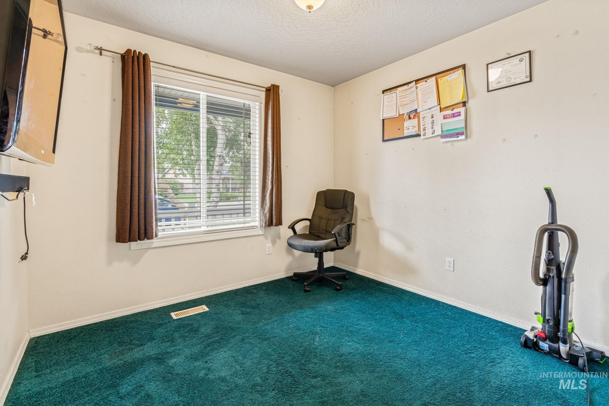 Unfurnished room featuring a textured ceiling and carpet floors