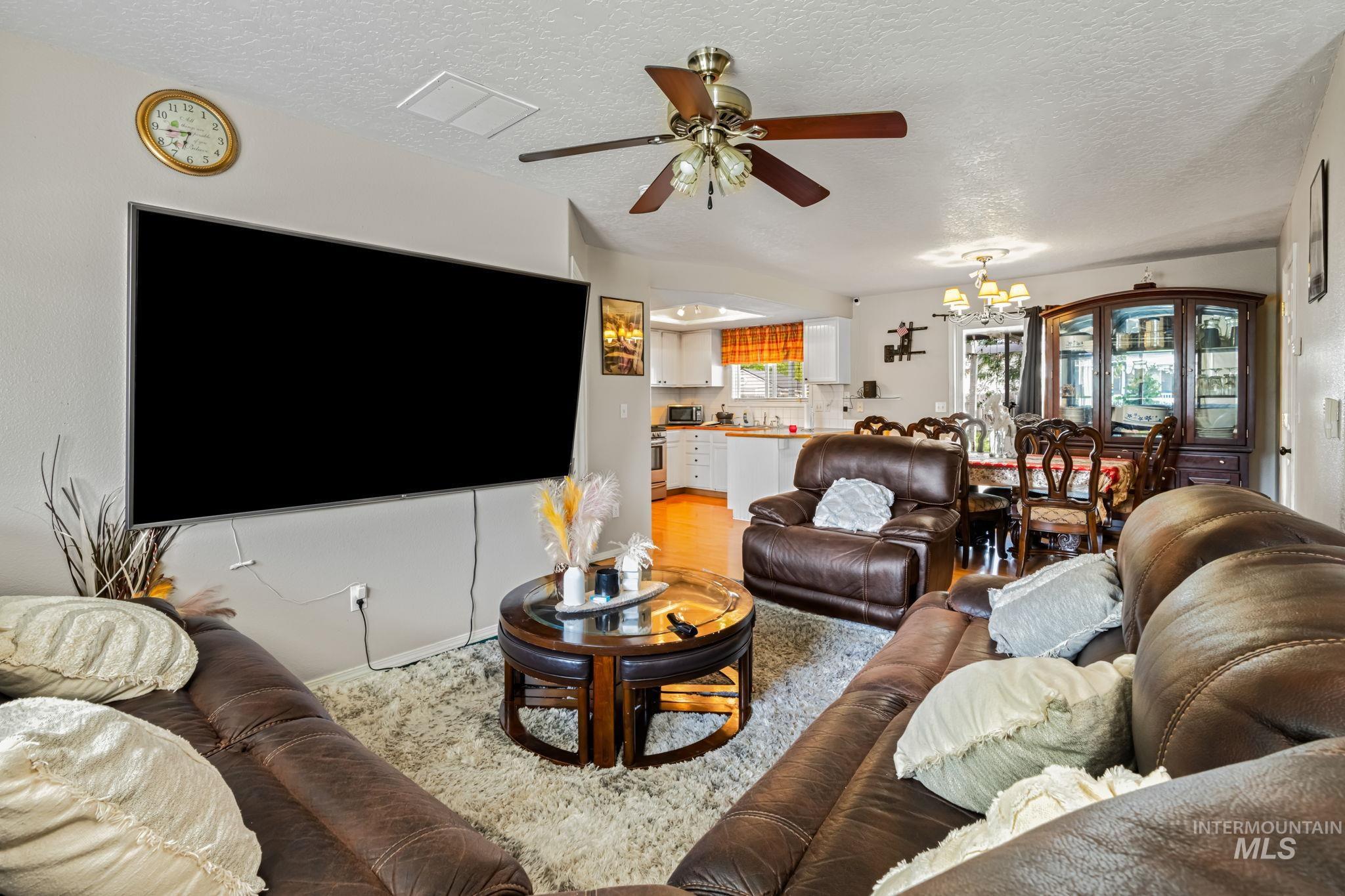 Living area with a chandelier, a textured ceiling, and ceiling fan