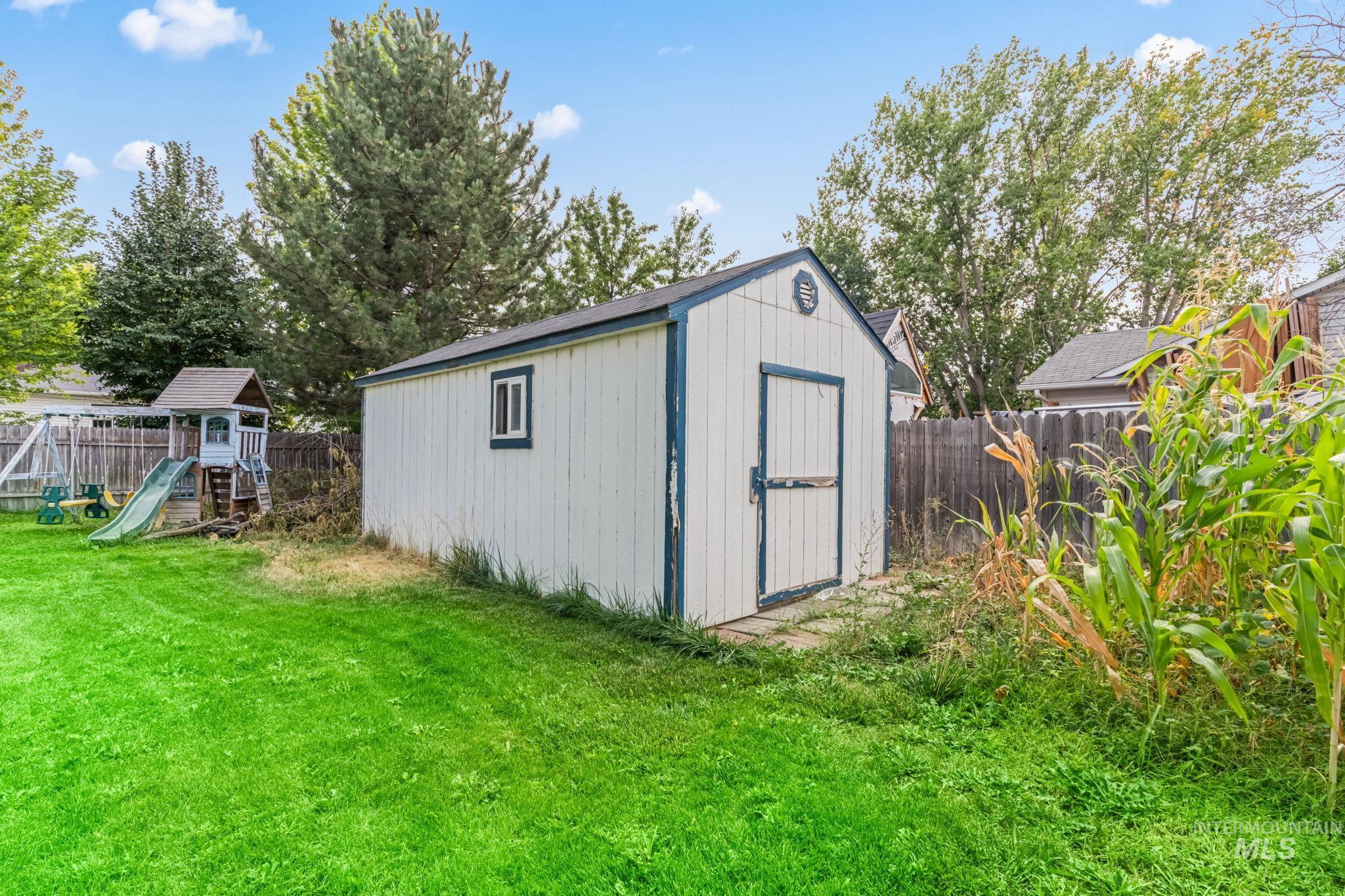 View of shed with a playground and a fenced backyard