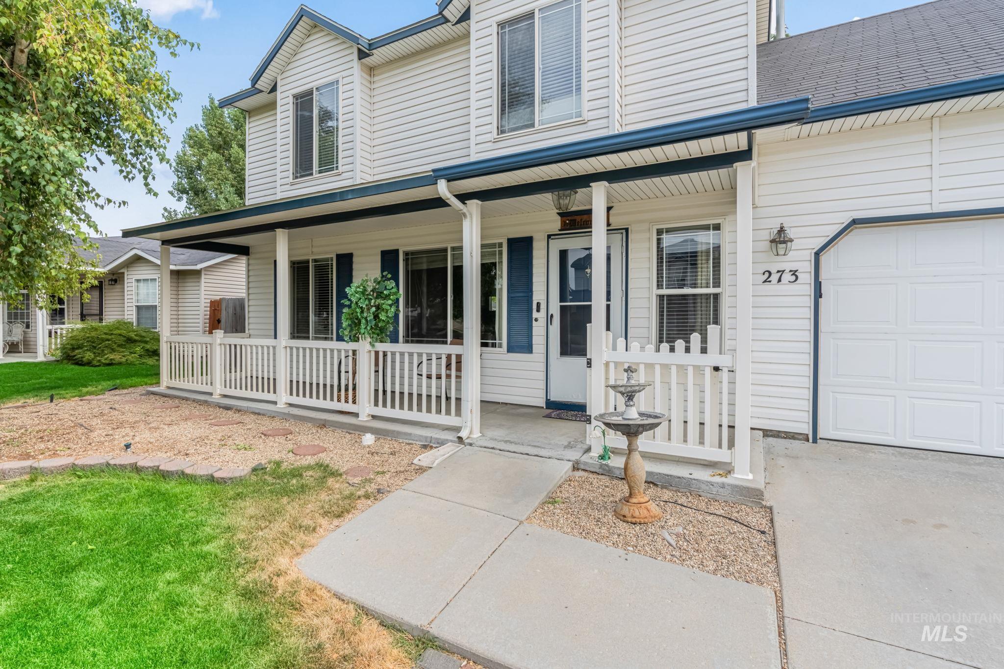 Doorway to property with a porch, an attached garage, and a yard