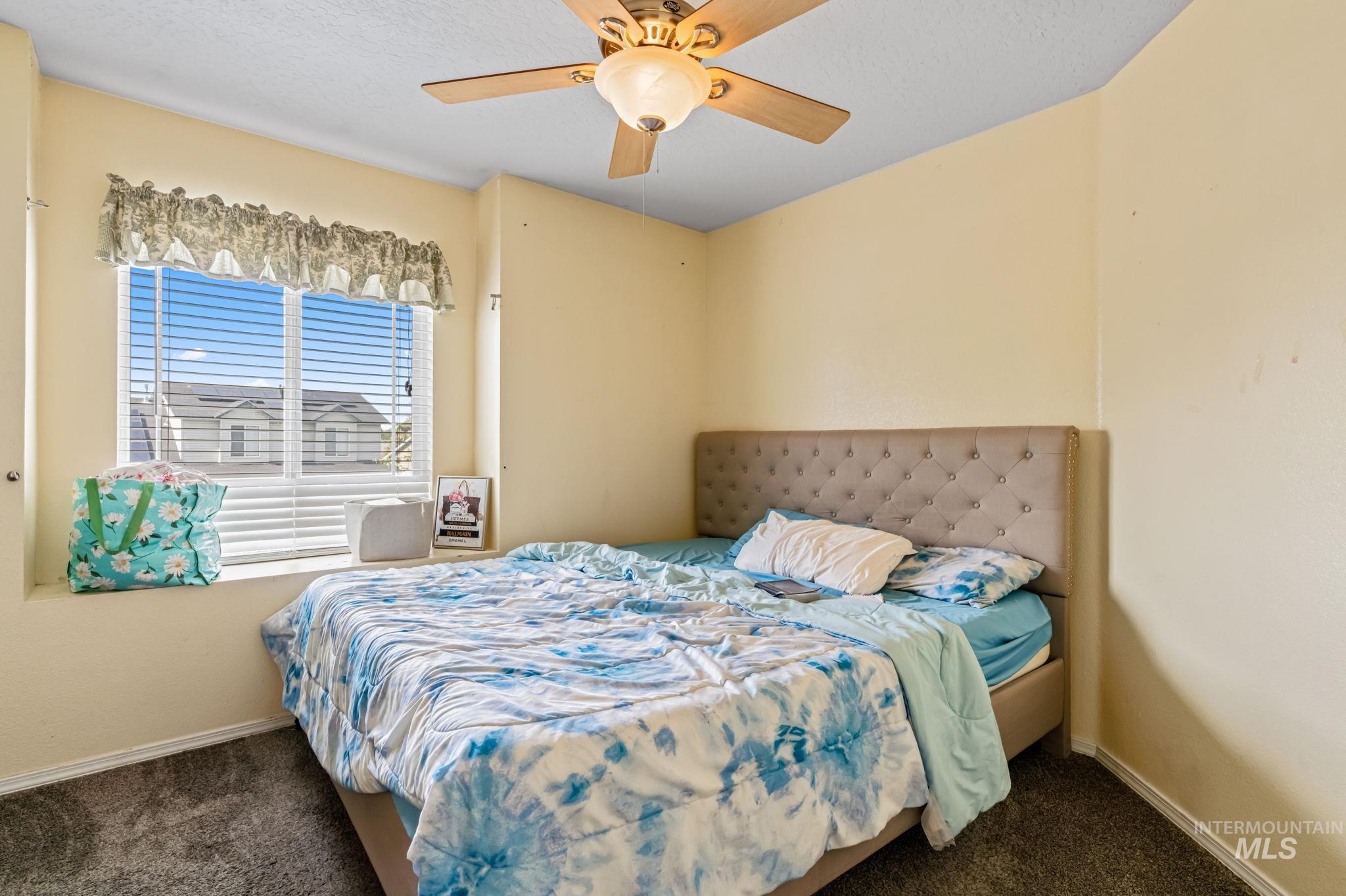 Carpeted bedroom with ceiling fan and a textured ceiling