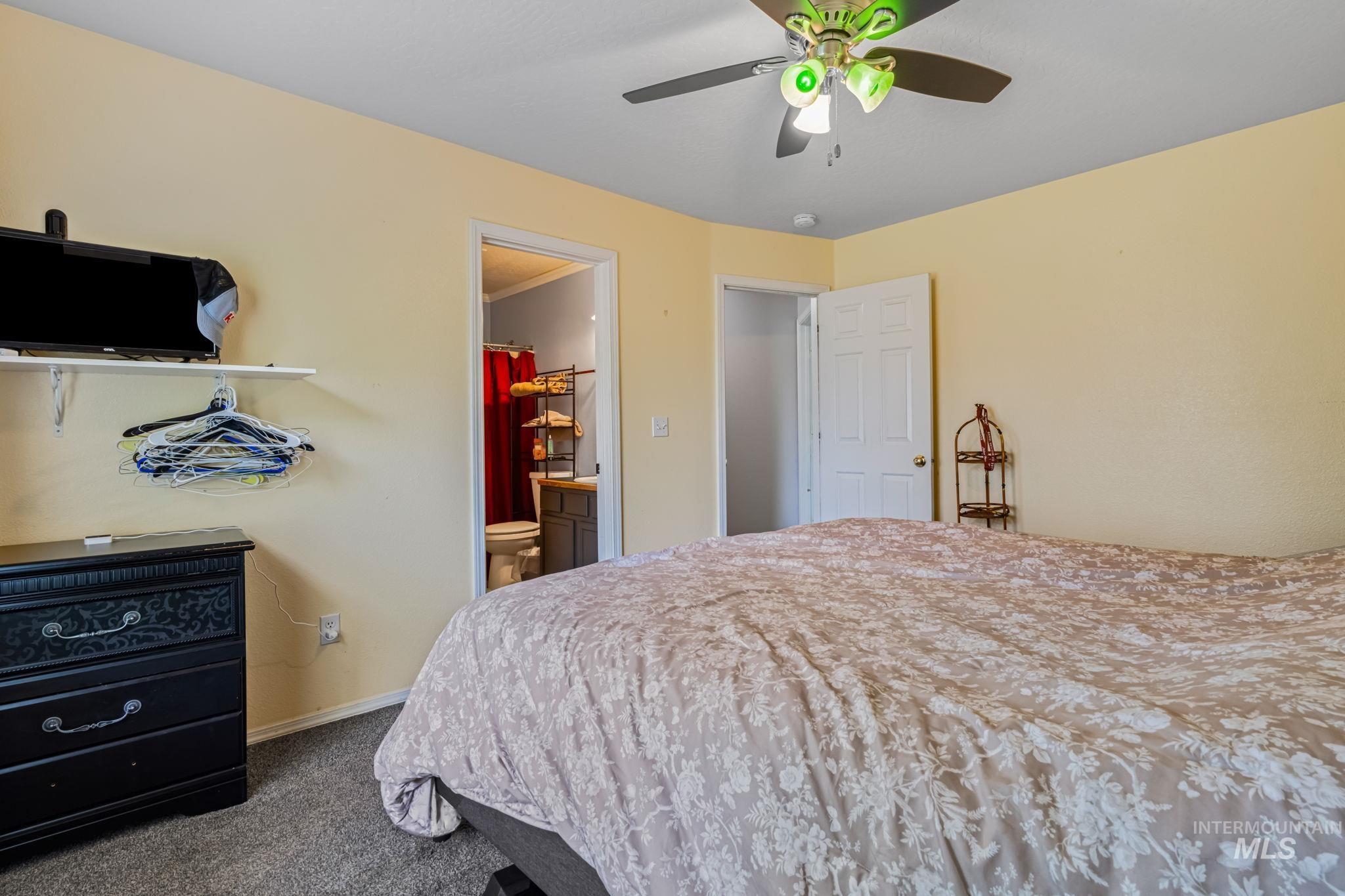 Bedroom featuring dark colored carpet, a ceiling fan, and ensuite bathroom