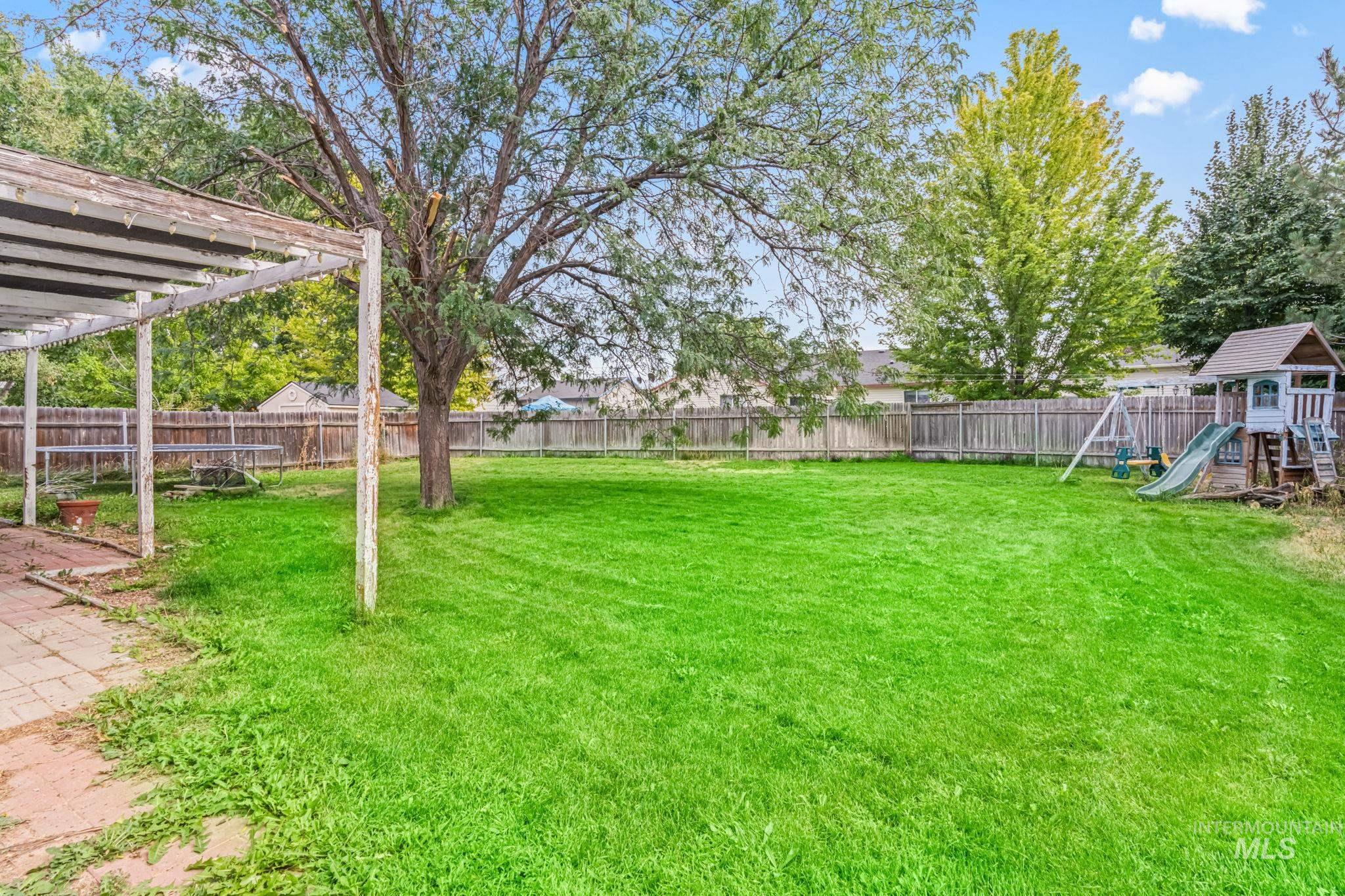 Fenced backyard featuring a playground