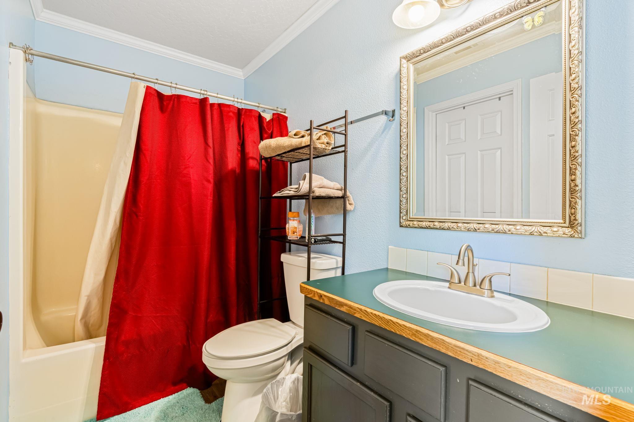 Bathroom with shower / bath combination with curtain, crown molding, vanity, and a textured wall