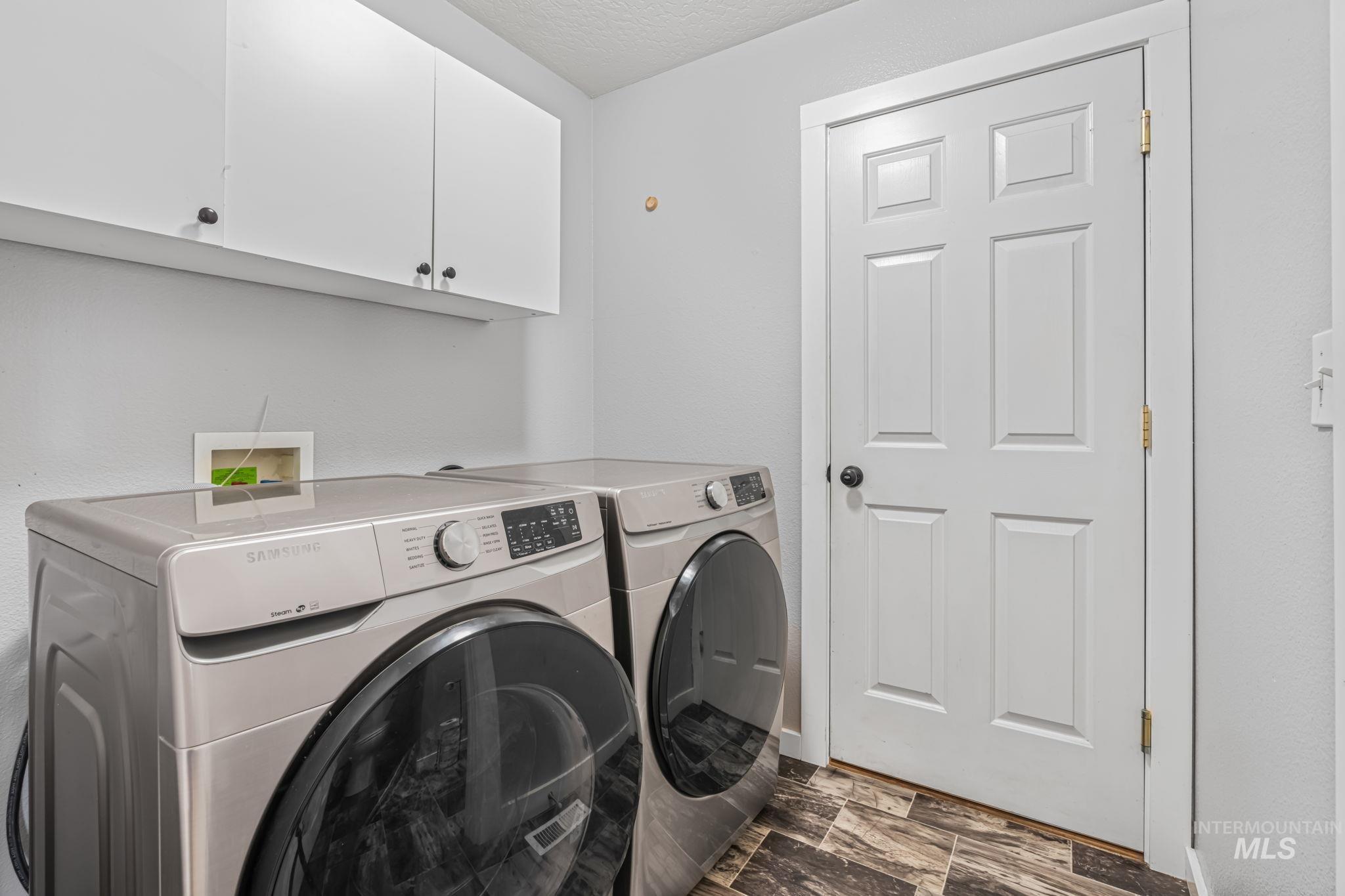 Laundry room with cabinet space, washer and dryer, a textured ceiling, and dark wood-style flooring