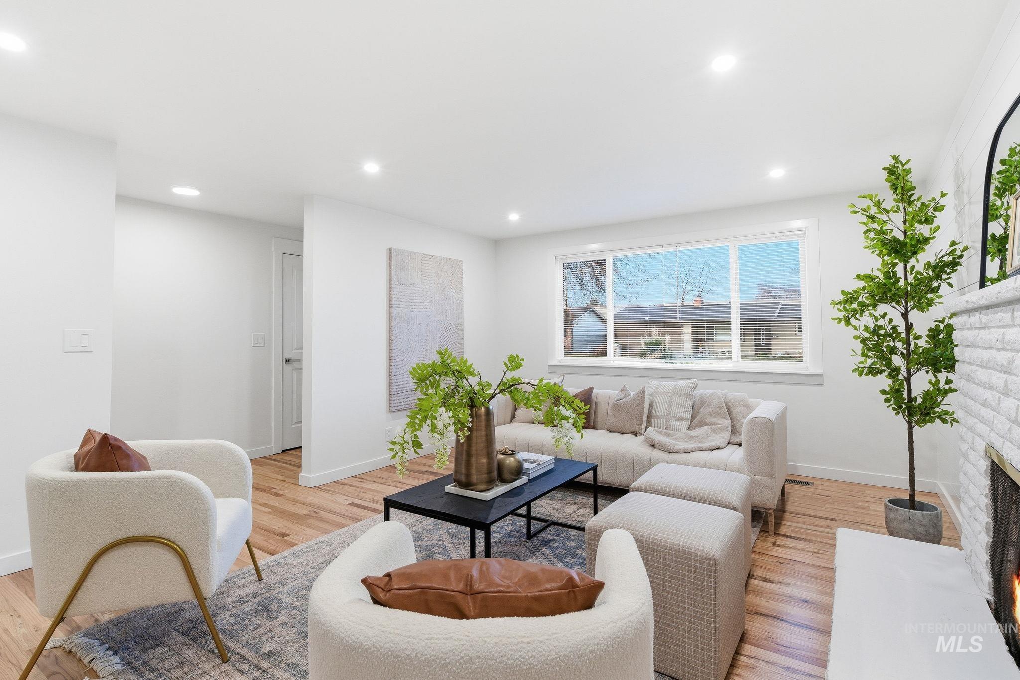 Living area with light wood finished floors, a brick fireplace, and recessed lighting