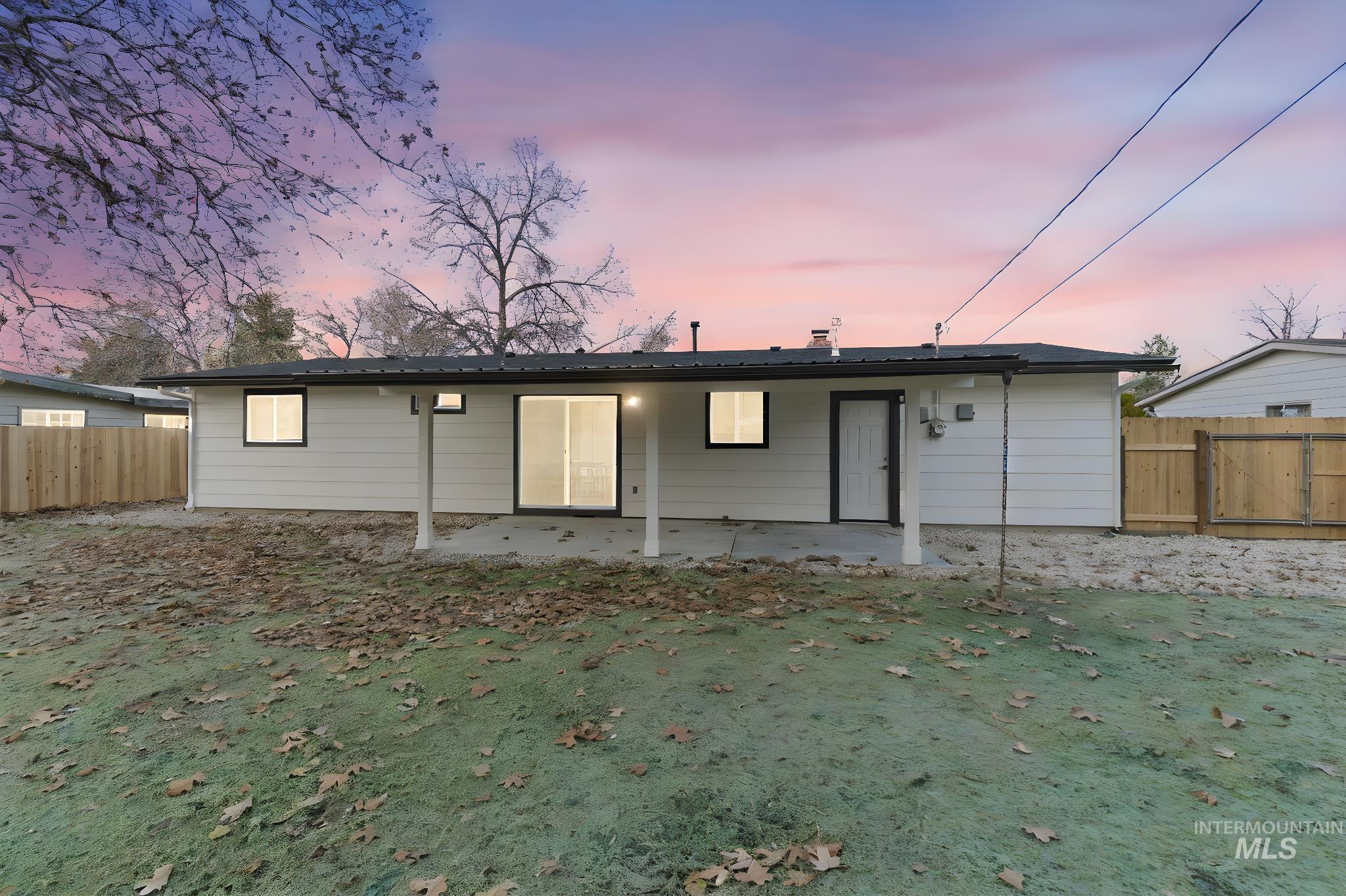 Back of property at dusk featuring a fenced backyard and a patio area