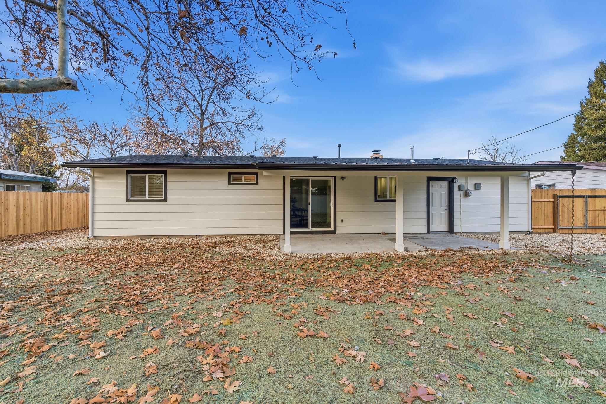 Rear view of house with a fenced backyard and a patio area