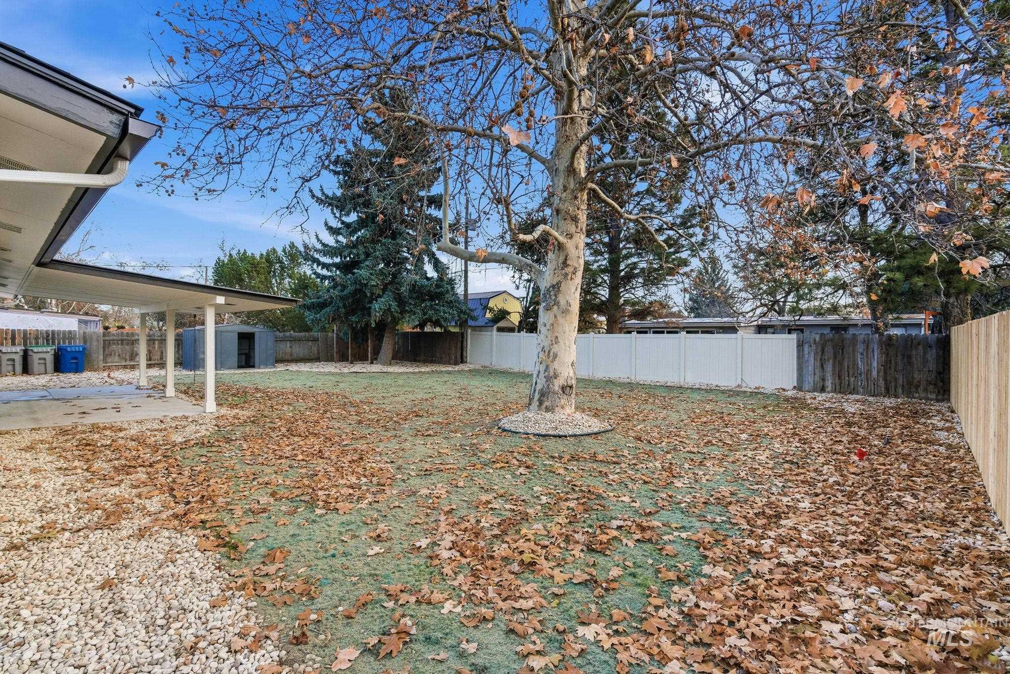 Fenced backyard featuring a storage unit and a patio area