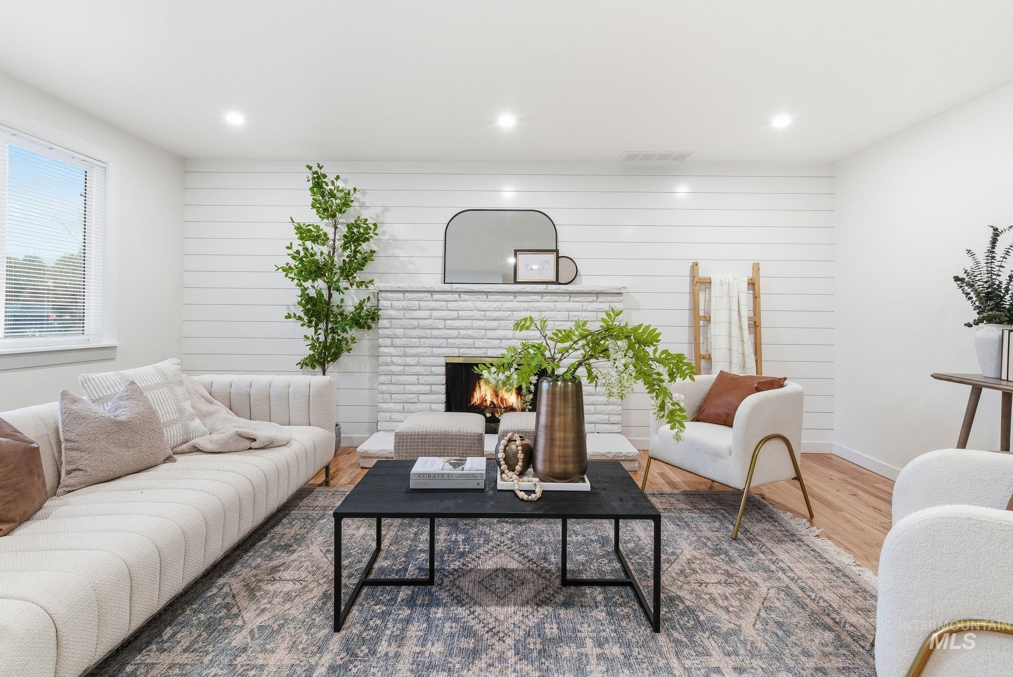 Living area with a fireplace, wooden walls, wood finished floors, and recessed lighting