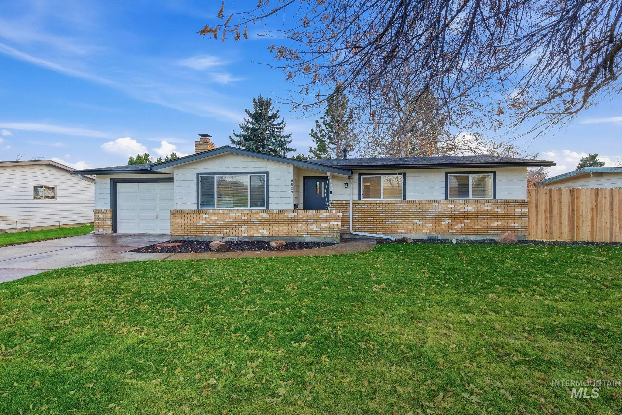 Ranch-style house featuring driveway, brick siding, a chimney, and an attached garage