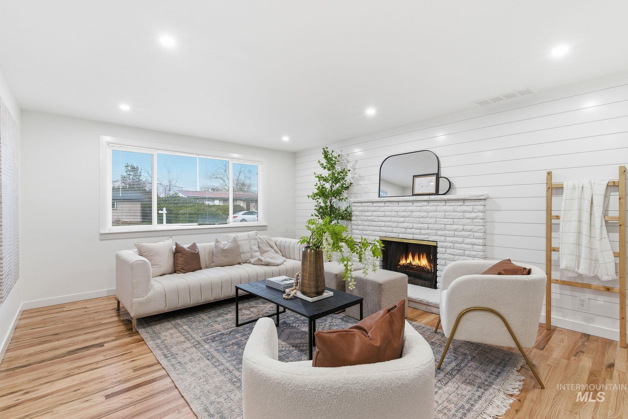 Living area featuring a fireplace, light wood-style floors, recessed lighting, and wooden walls