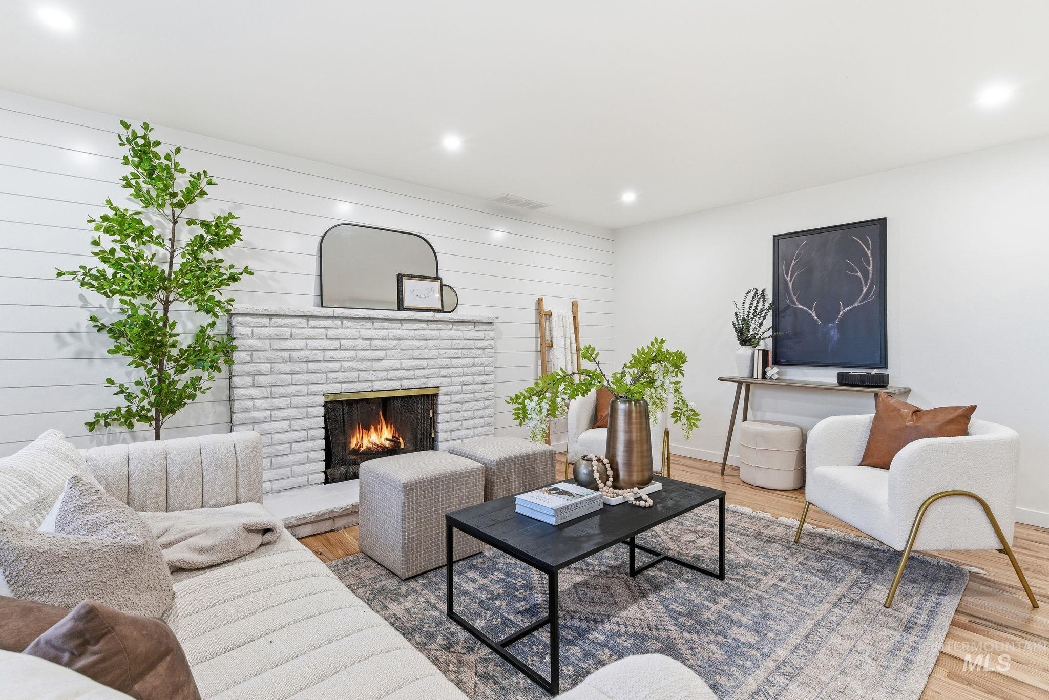 Living area with a fireplace, light wood-style floors, wood walls, and recessed lighting