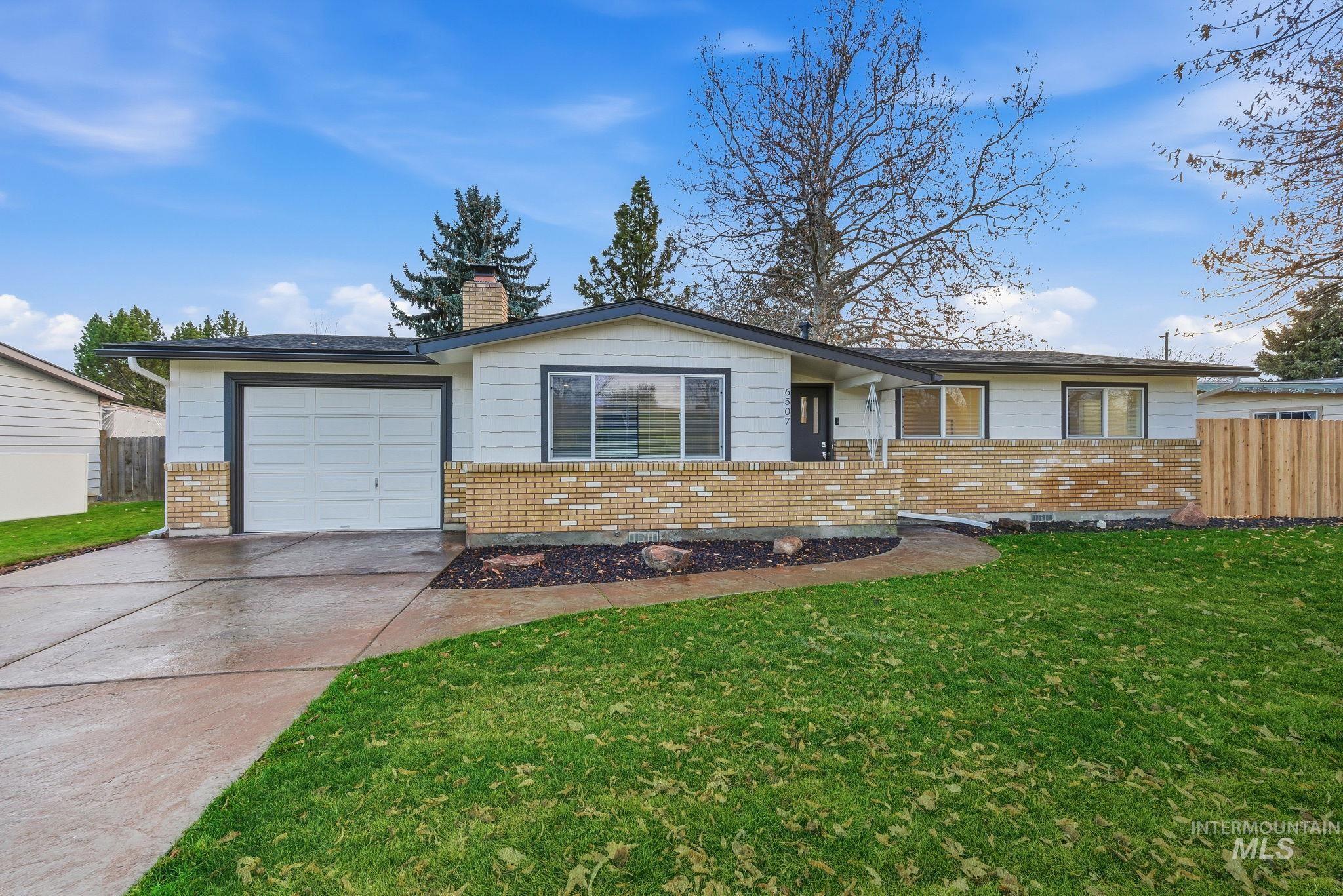 Single story home with driveway, a chimney, an attached garage, and brick siding