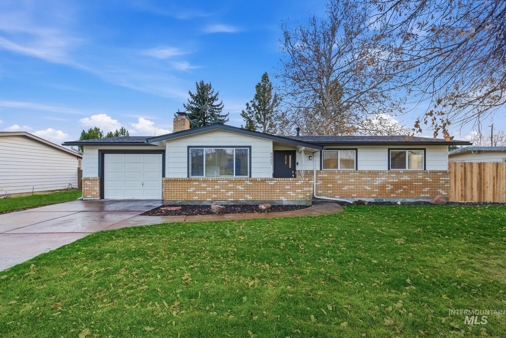 Ranch-style home featuring brick siding, driveway, a chimney, and a garage