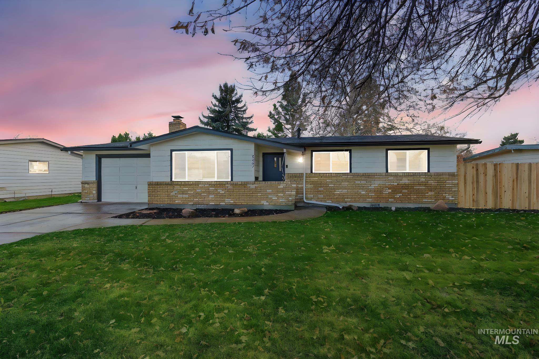 Ranch-style home with brick siding, driveway, a chimney, and a garage
