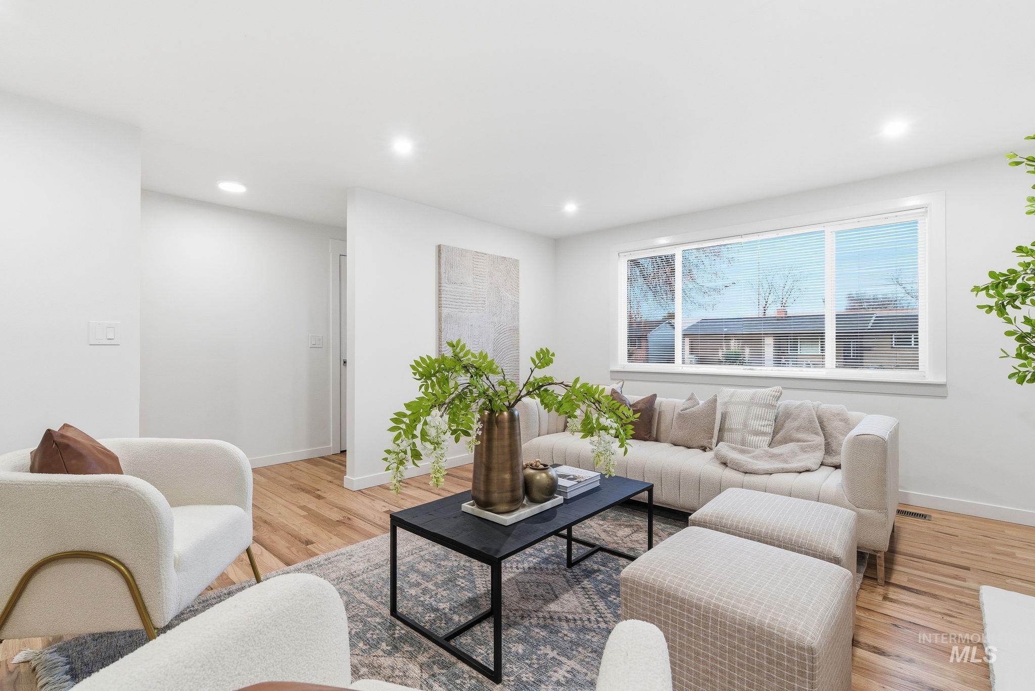 Living area with light wood-type flooring and recessed lighting