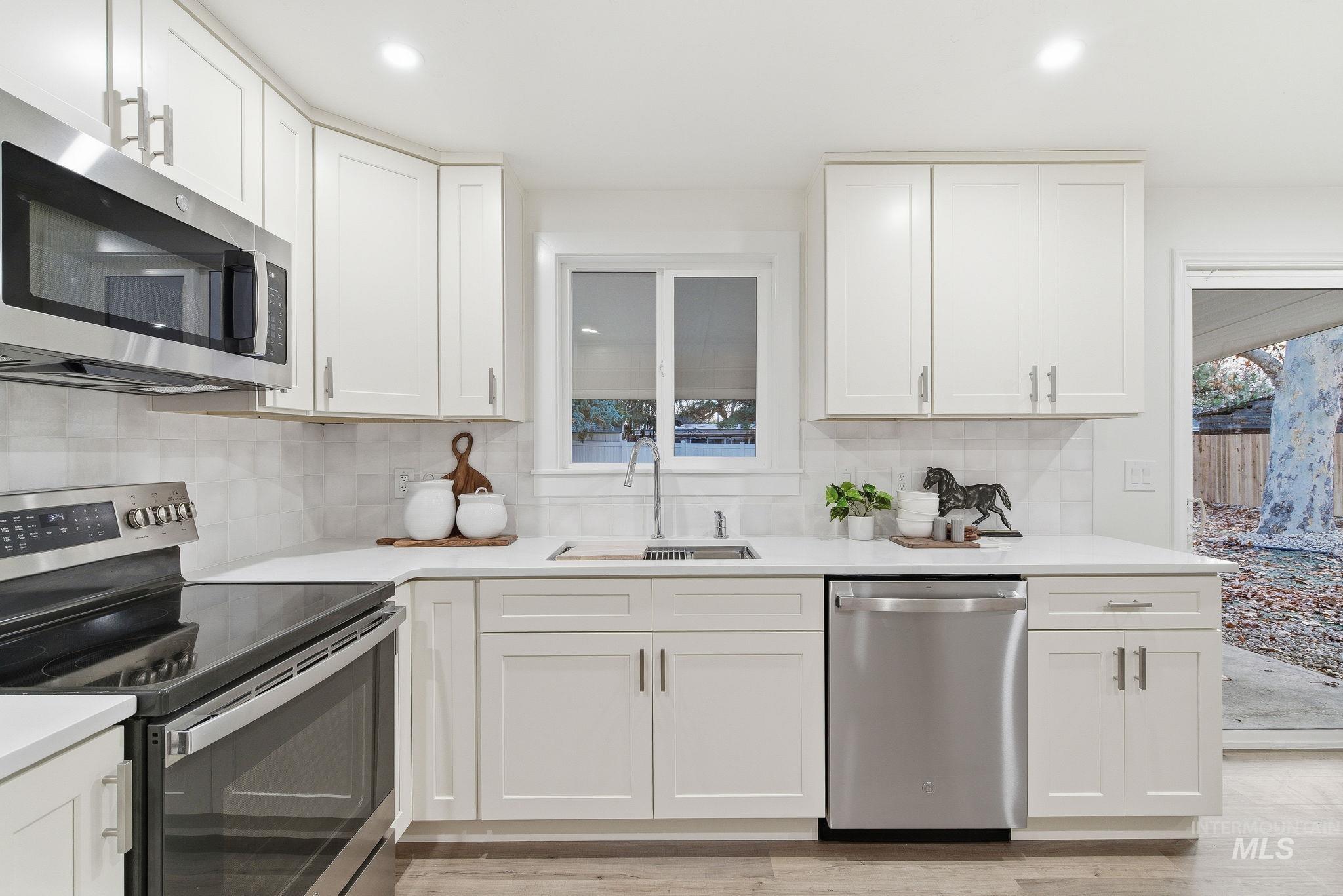 Kitchen featuring appliances with stainless steel finishes, white cabinets, decorative backsplash, and recessed lighting